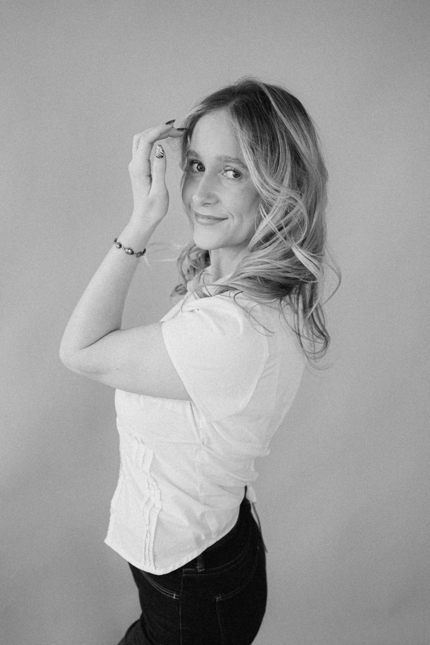 A series of black and white portraits showing someone in a white top posing playfully against a plain background.
