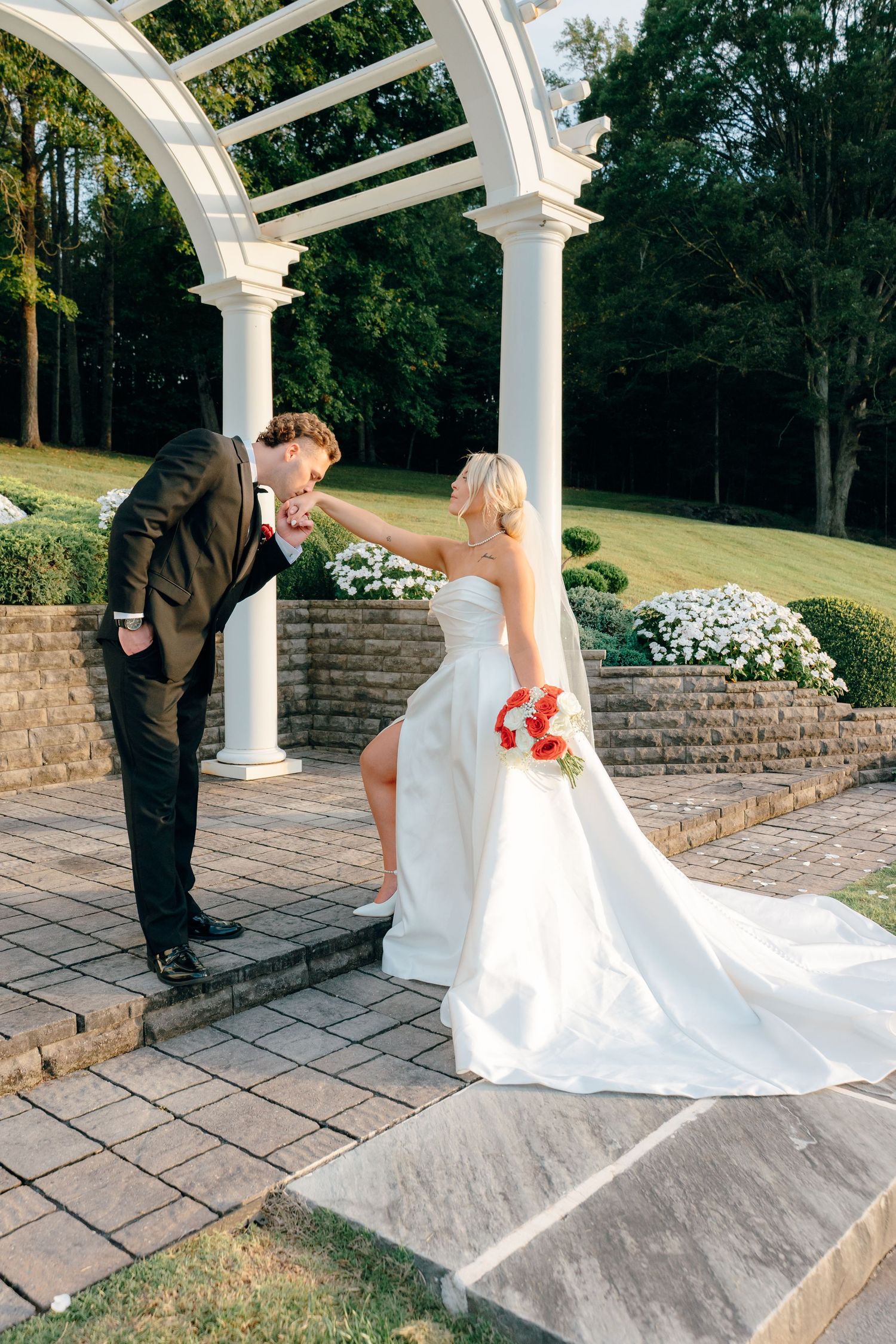 Wedding couple sharing intimate moments under an elegant white archway and stone patio.