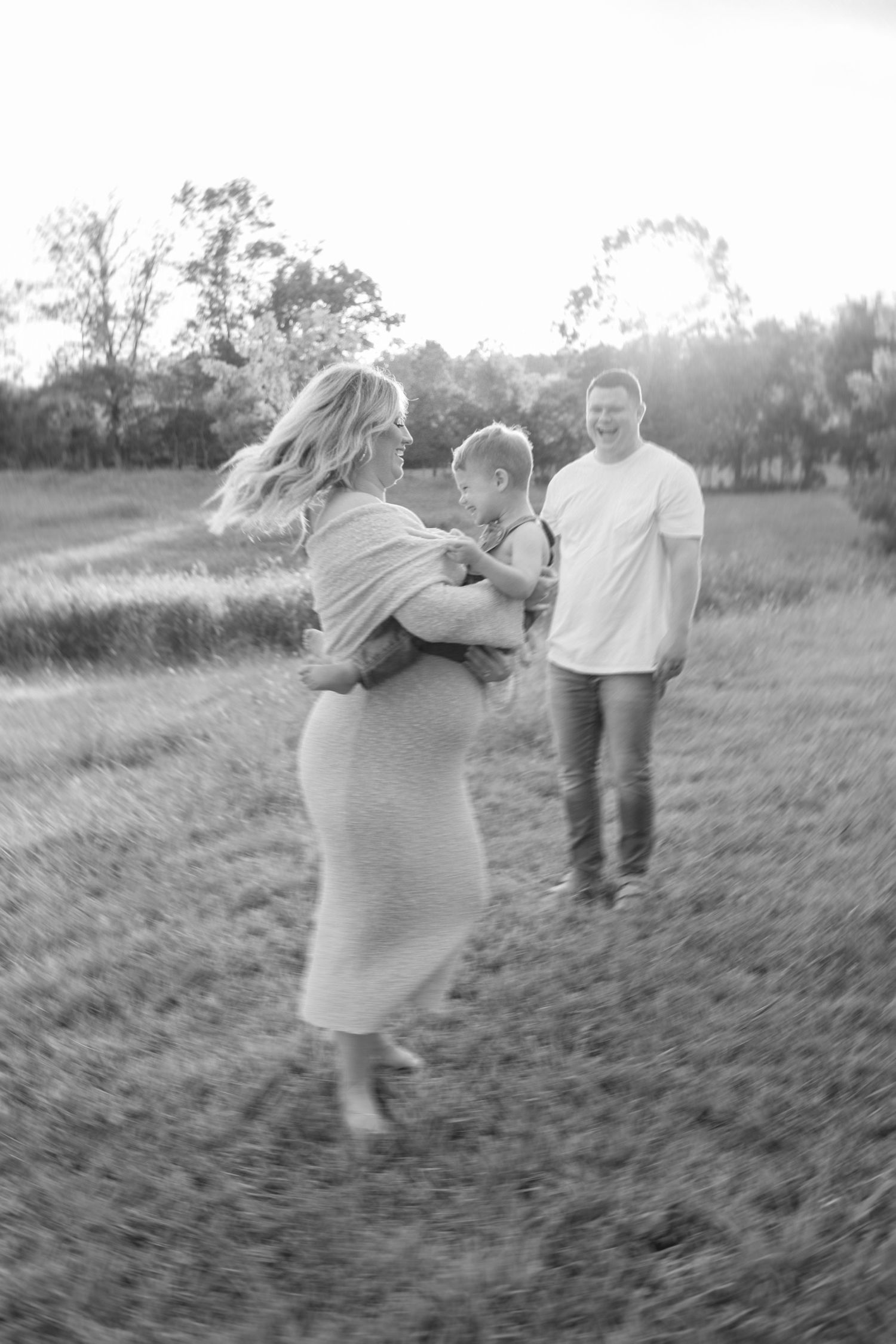 A black and white series of a family playing together in a grassy field.