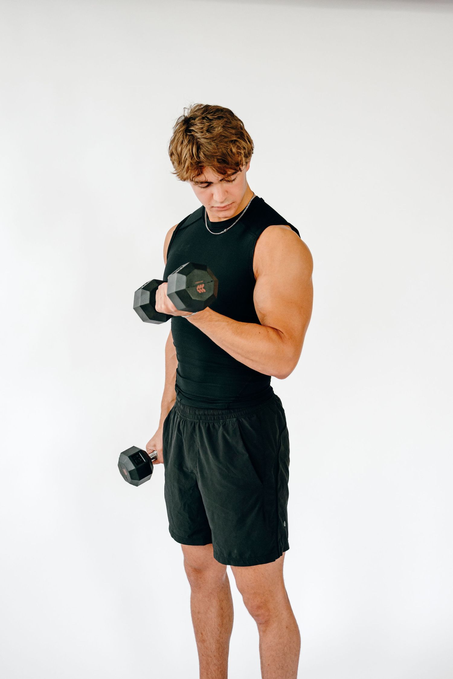 Fitness demonstration showing proper dumbbell curl form in black athletic wear.