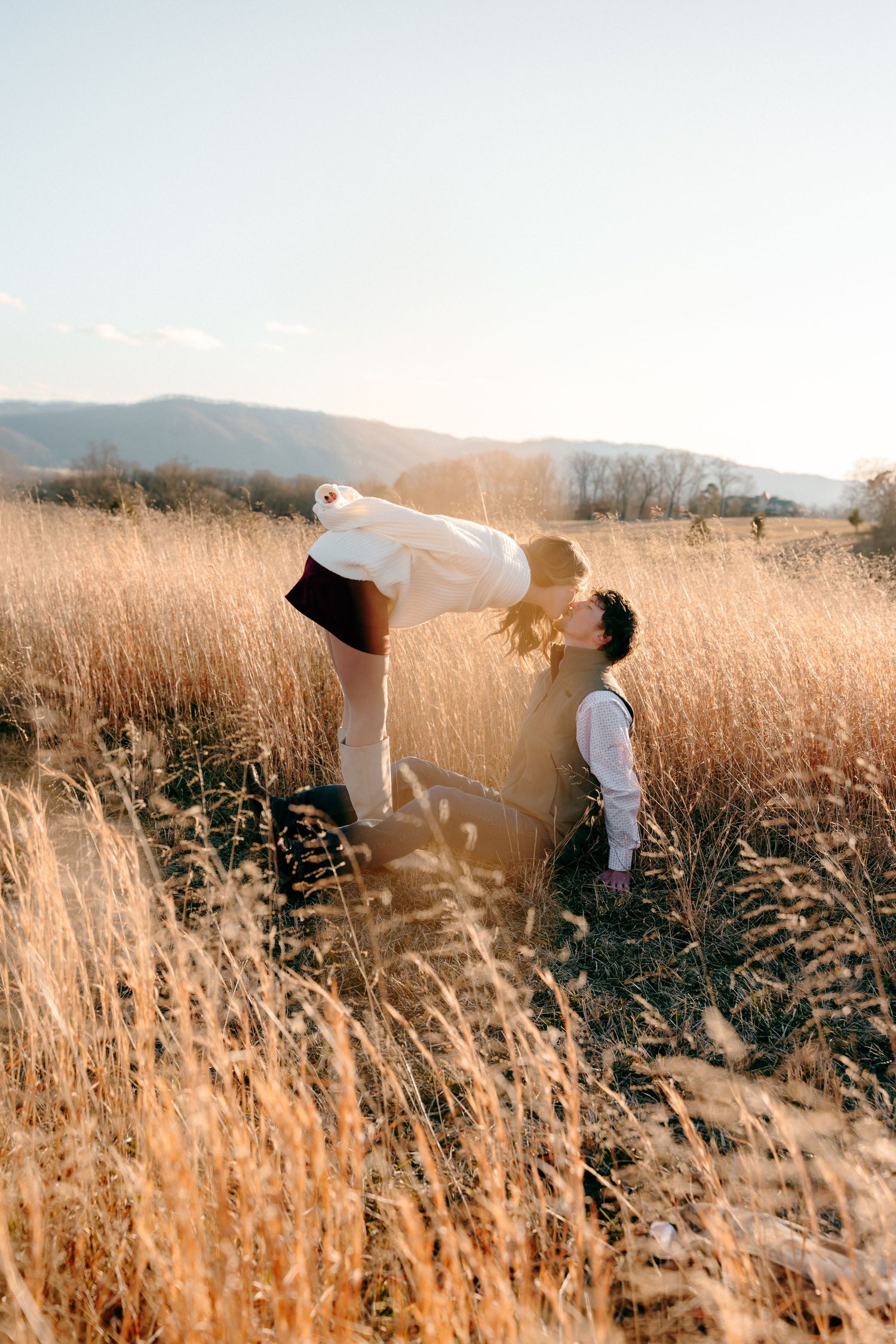 Romantic couple embracing in a golden wheat field during sunset.