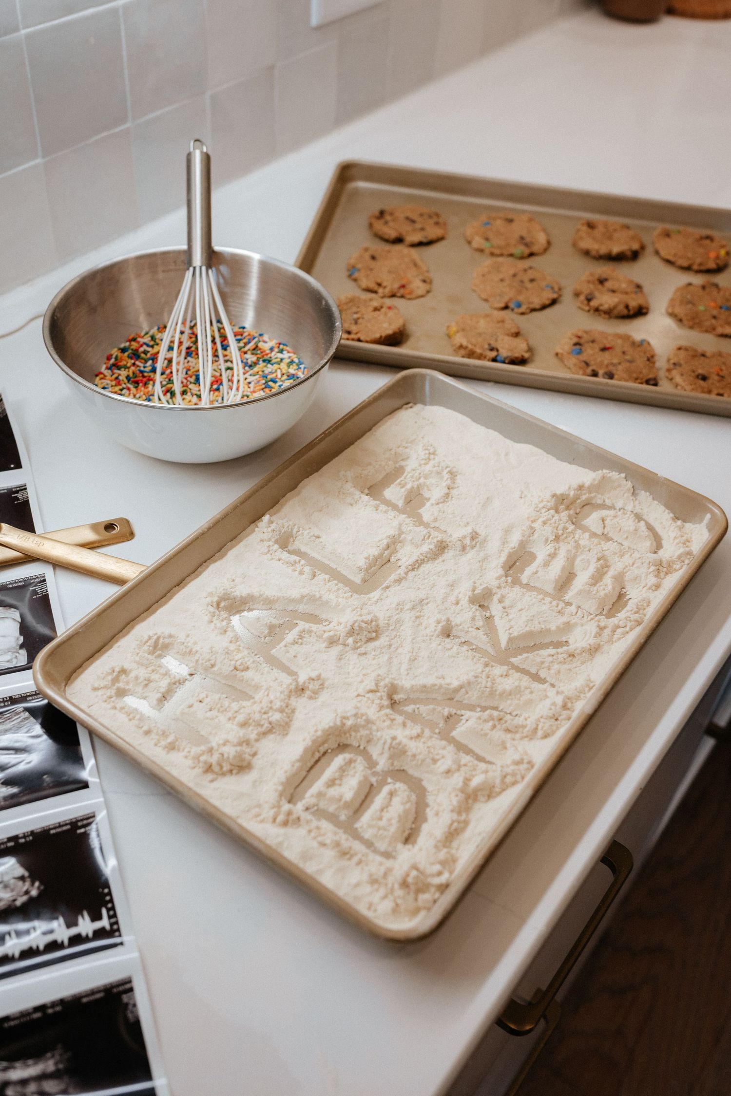 A series of baking trays showing the process of making chocolate chip cookies in the kitchen.