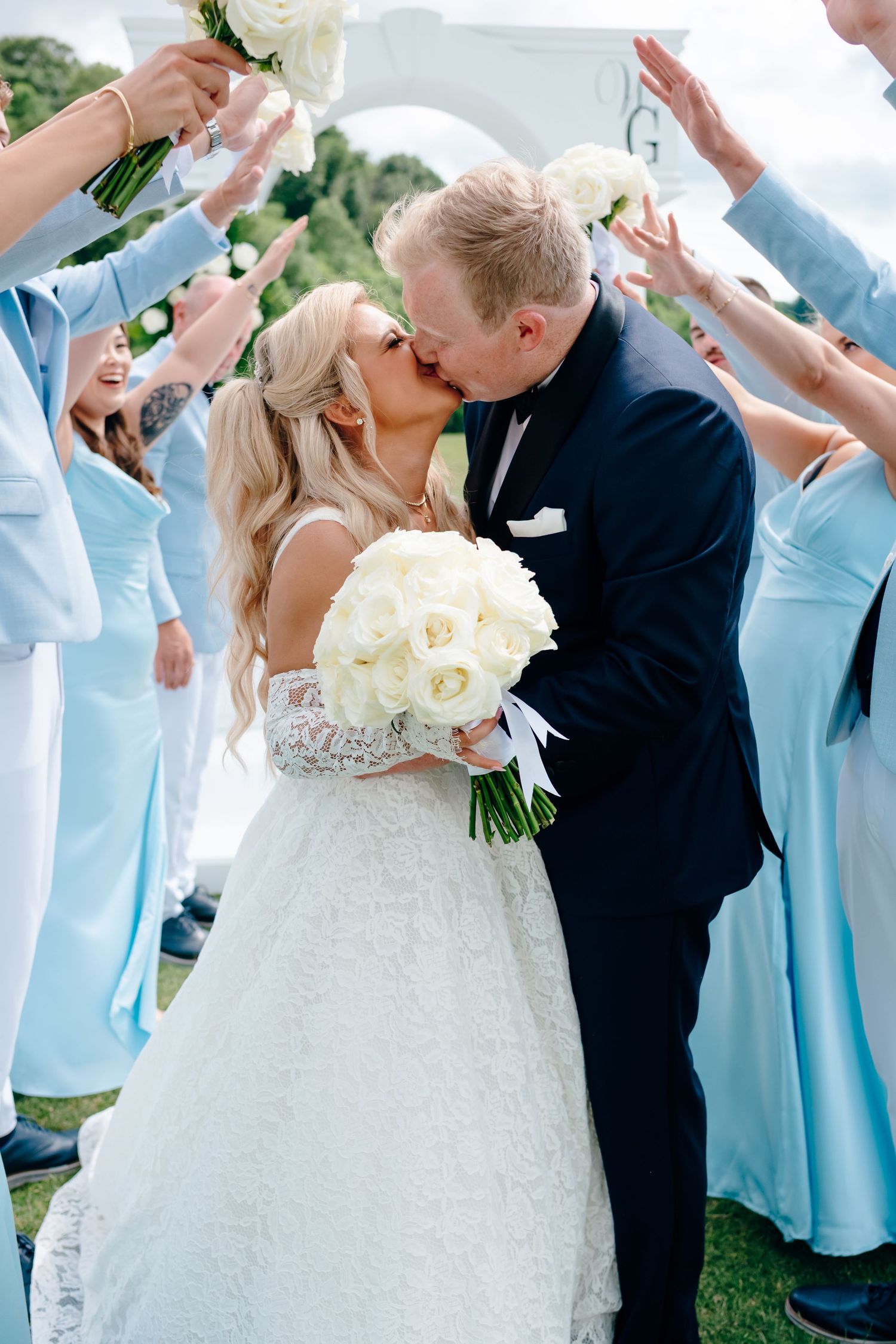 Wedding celebration with bridesmaids in blue dresses cheering newlyweds.