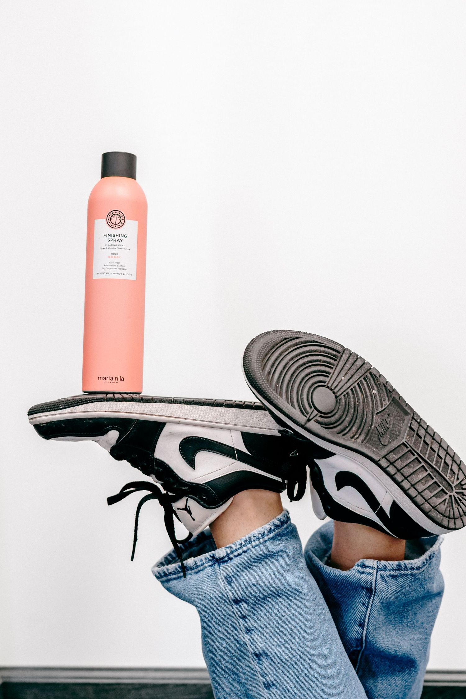 Pink shampoo bottle and black sneakers arranged with blue jeans in a creative product photography composition.