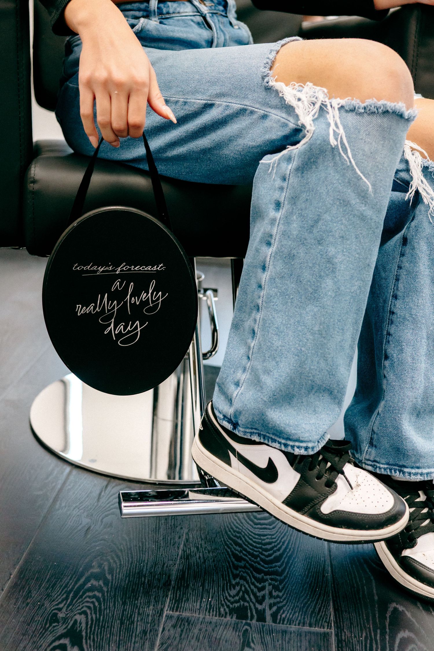 Close-up of denim jeans and Nike sneakers with black circular signs in a salon setting.