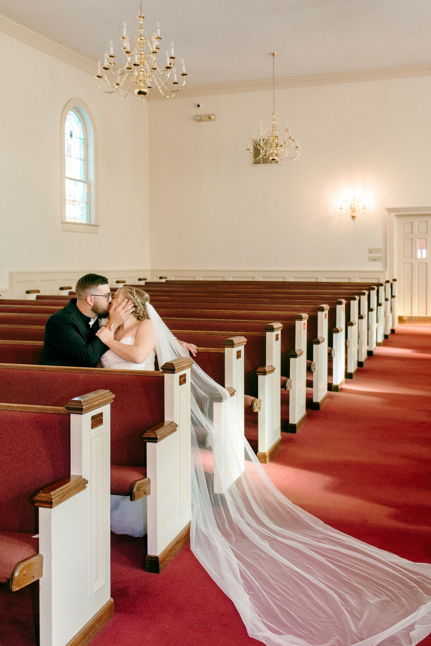 Wedding photos in a traditional church with red carpet and long flowing veil.