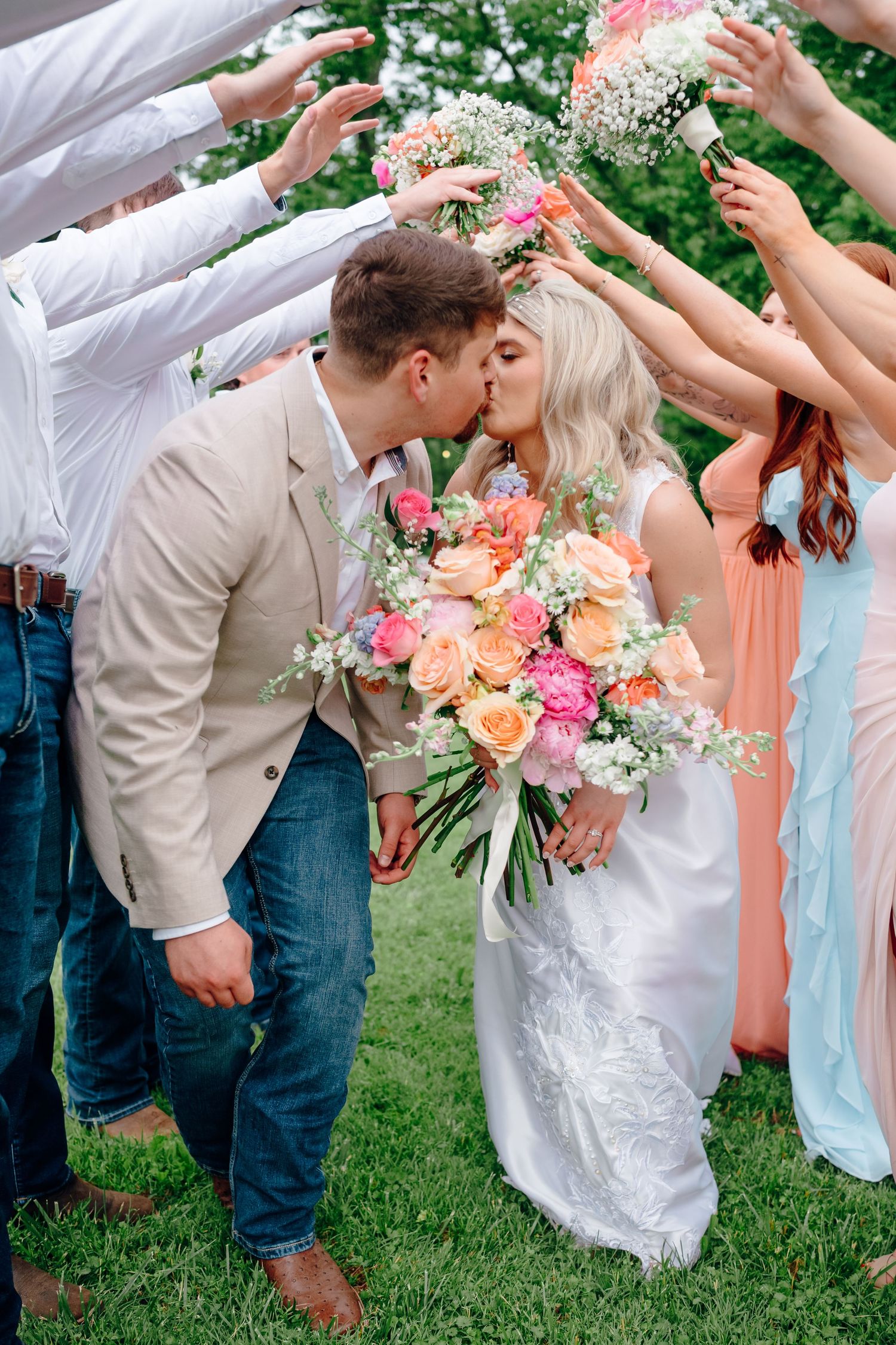 Wedding party celebrating with champagne sprays in an outdoor garden setting.