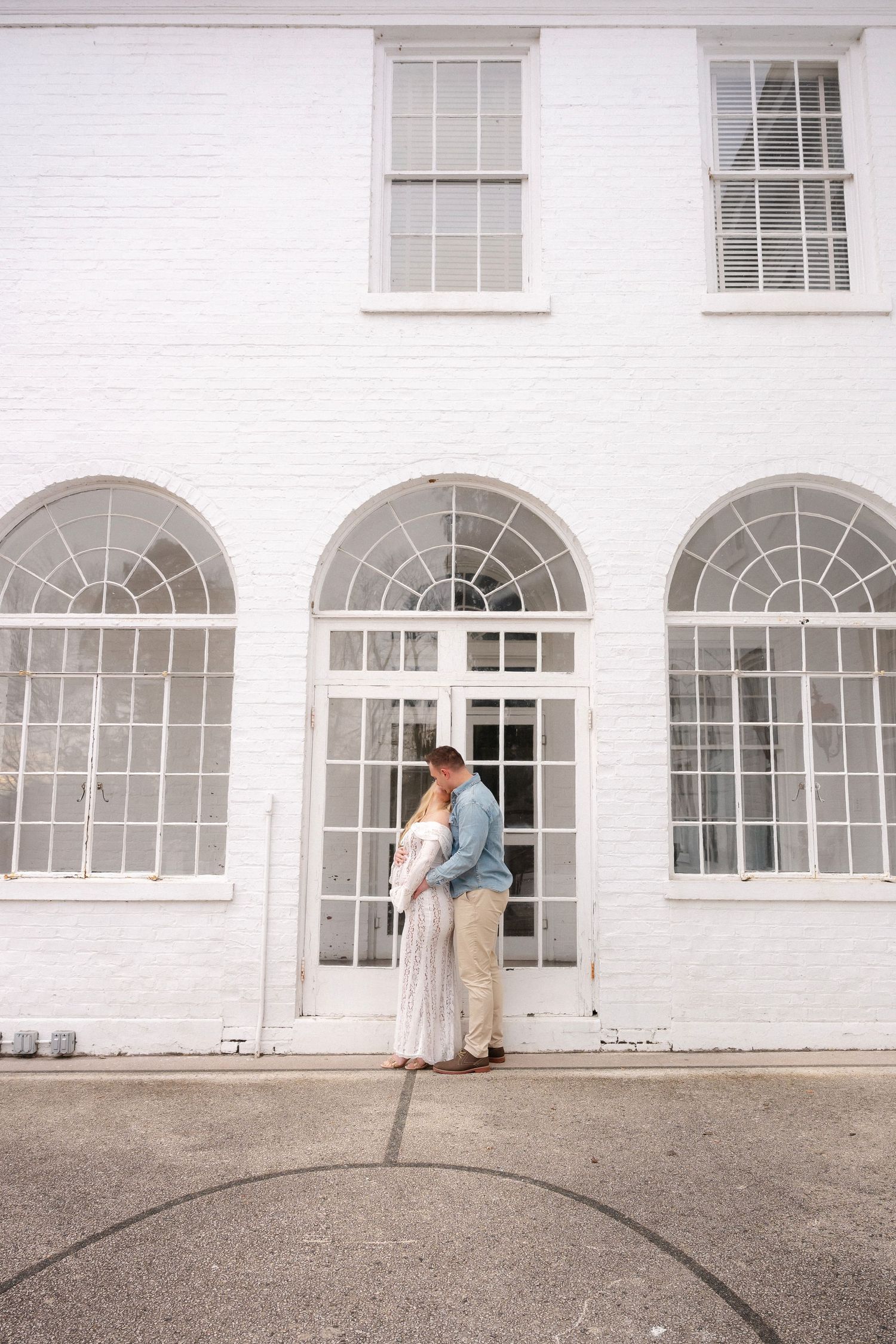 A romantic scene unfolds against a white building with arched windows and columns.