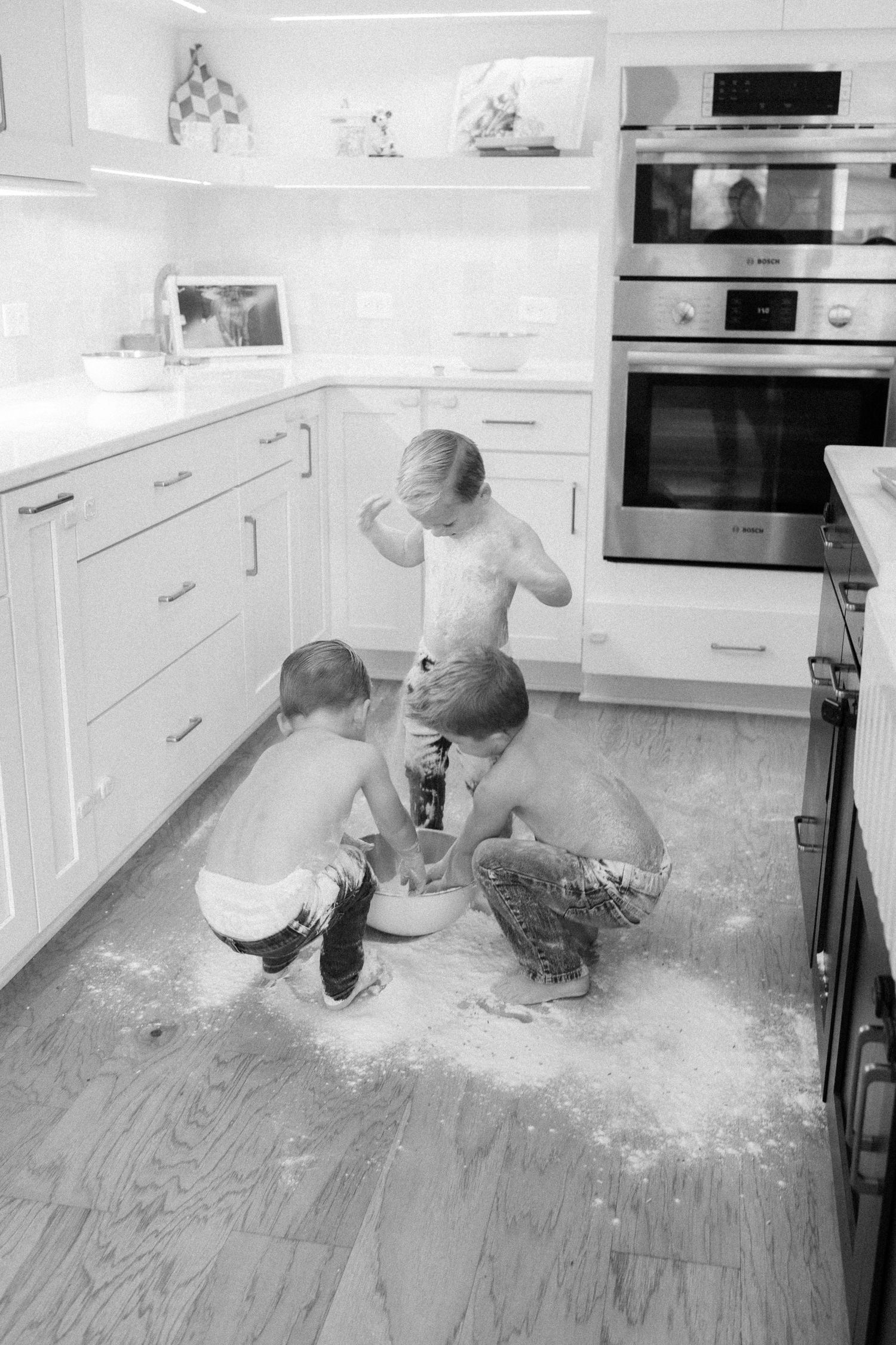 Playful scene of flour being tossed around on a kitchen floor creating a mess.