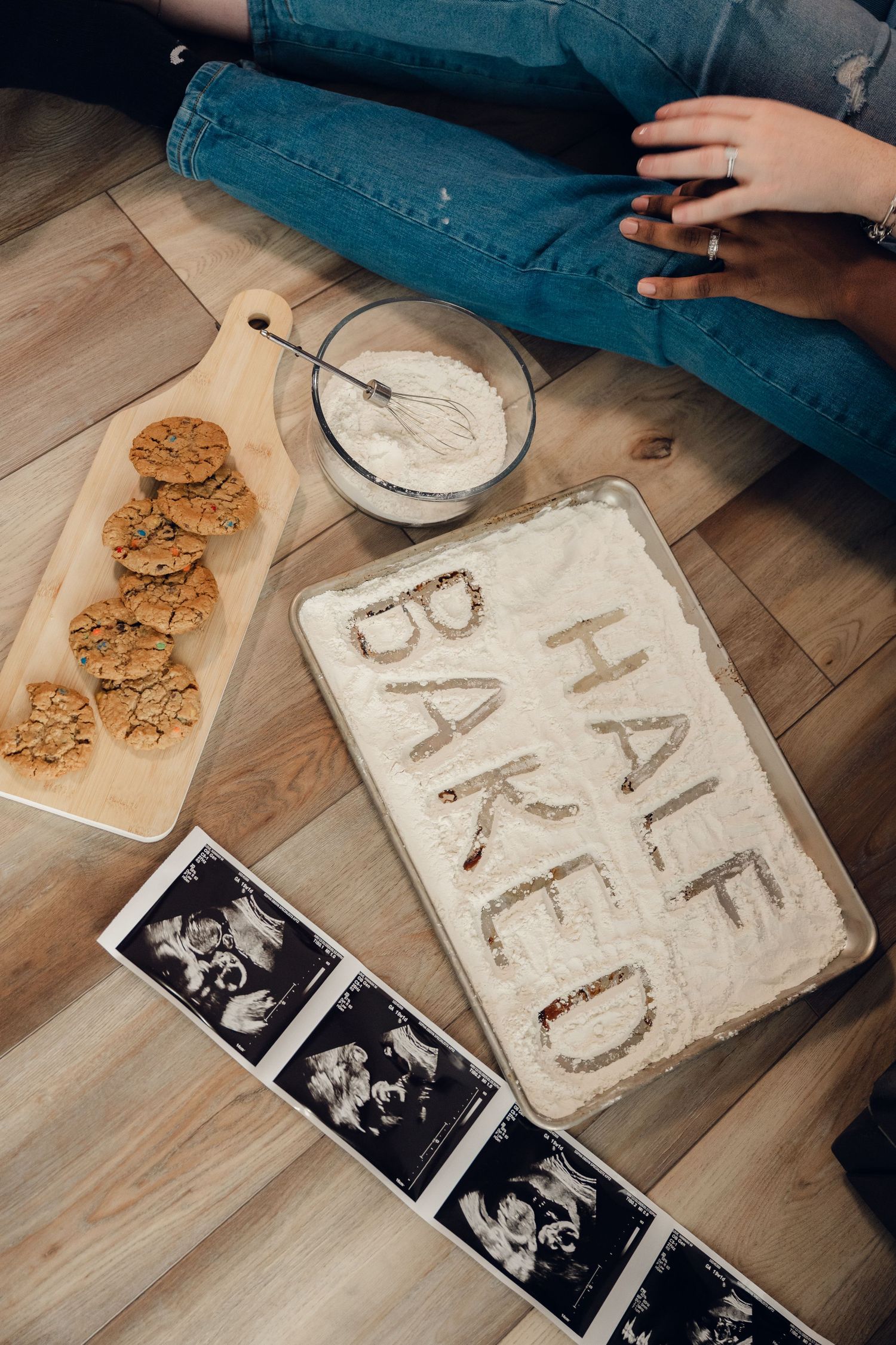 Flour writing and cookies on wooden cutting board with ultrasound photos.