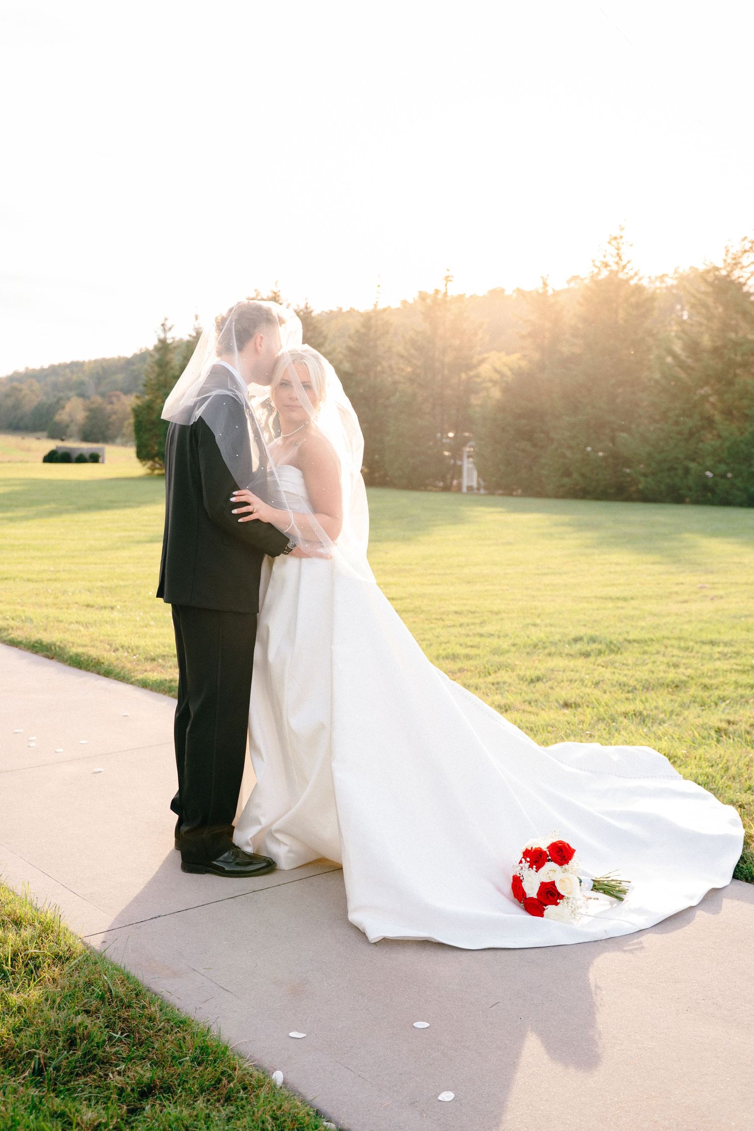 A romantic sunset wedding photo series showing a bride's flowing white dress and red bouquet against a golden field.