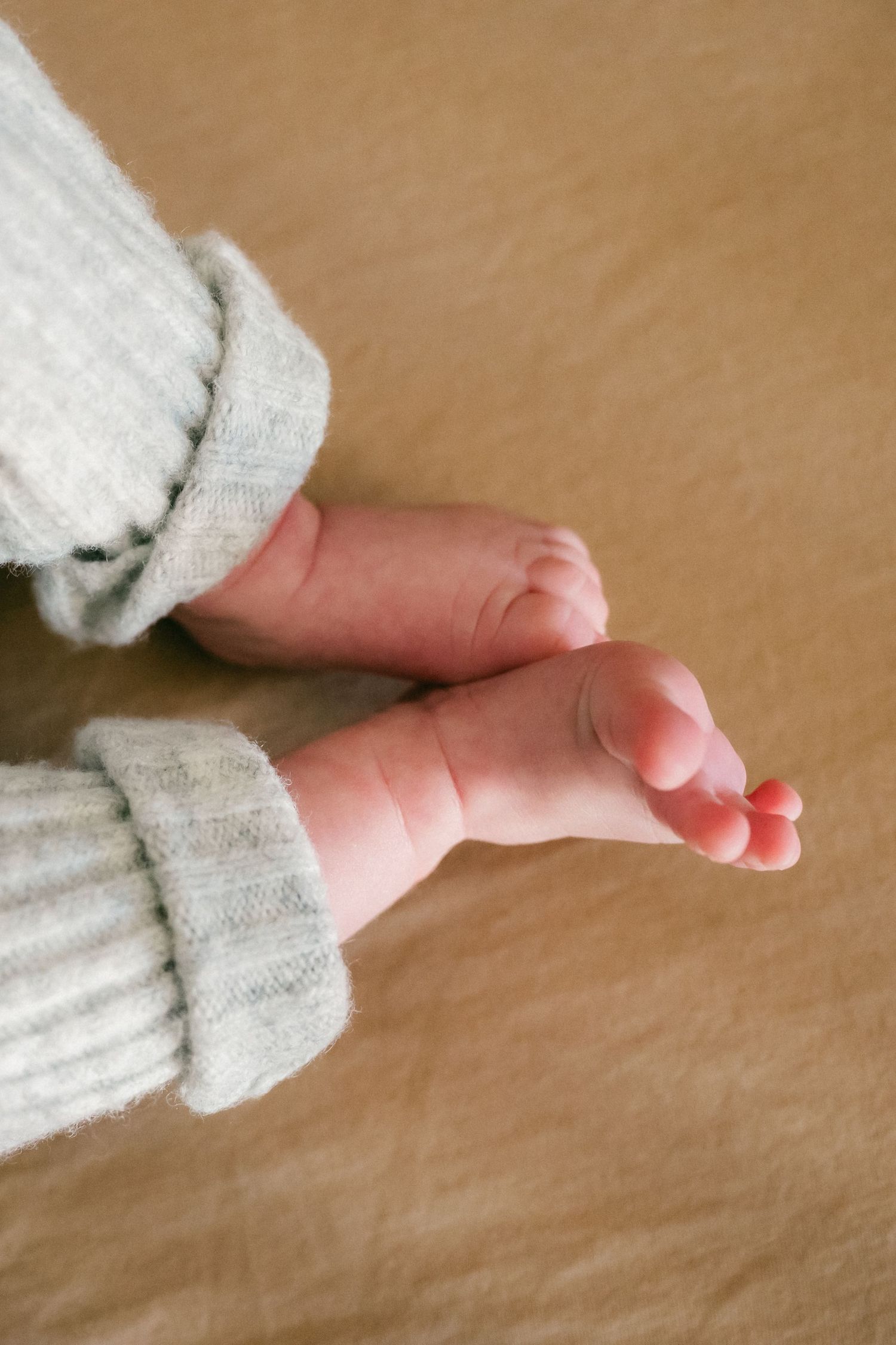 Close-up shots of tiny baby feet in white clothing against a beige background.