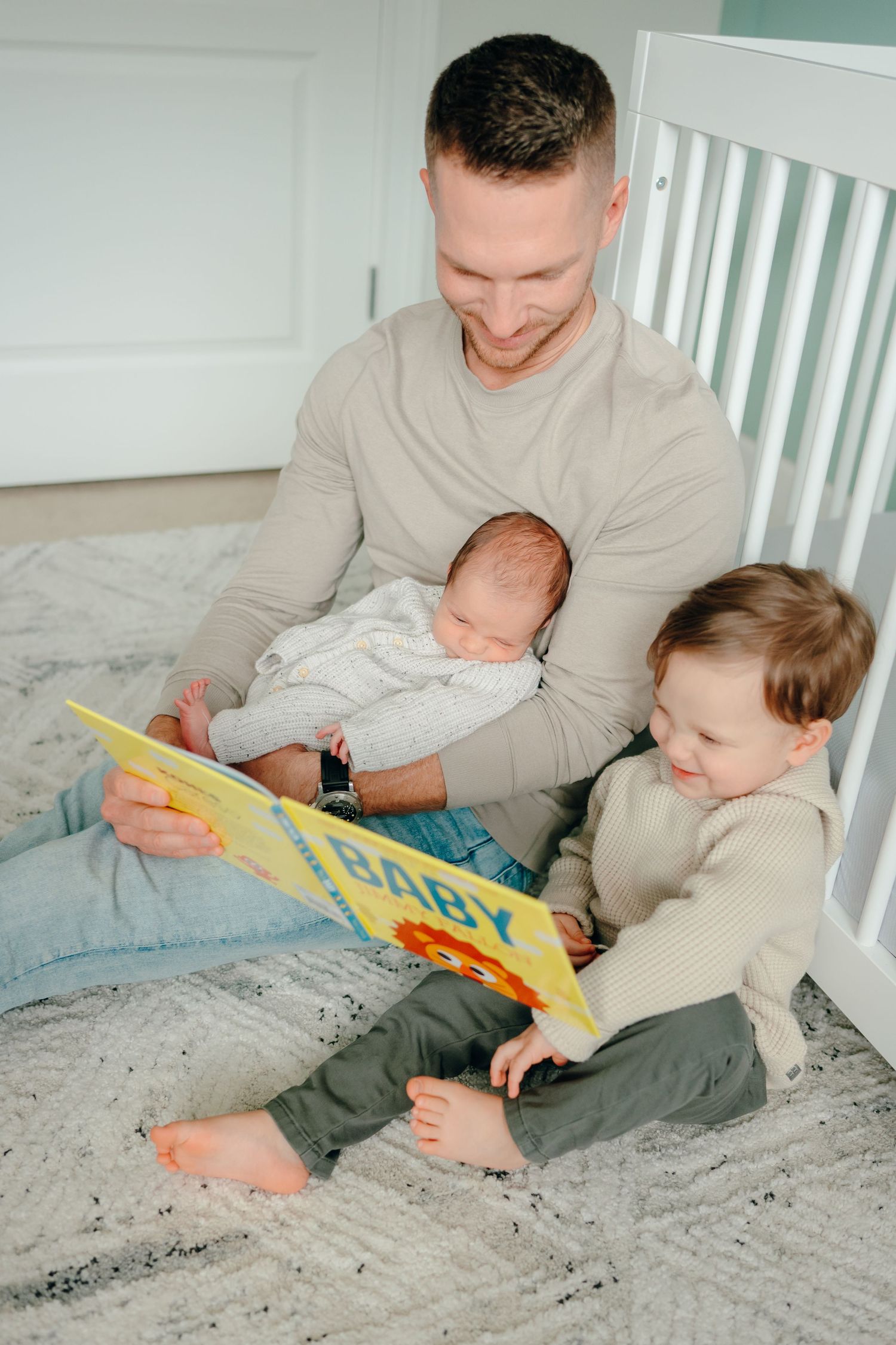 Family reading time with children on gray bedding.