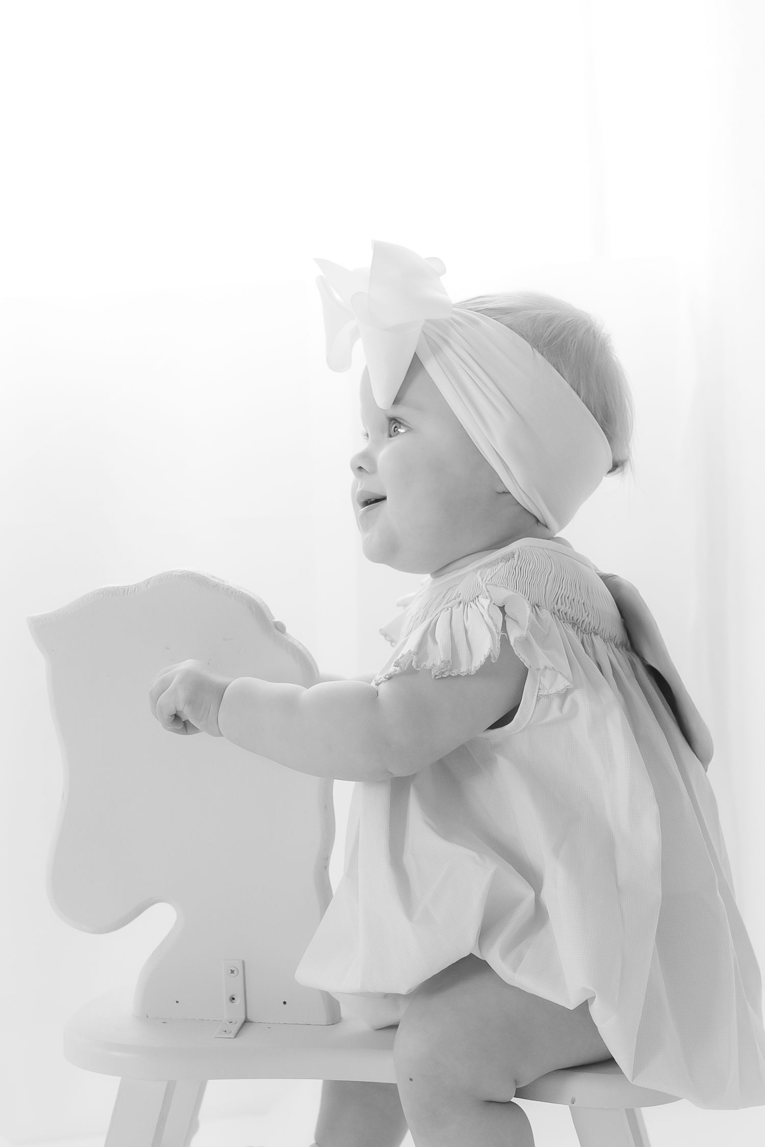 A series of black and white photos showing a baby in white clothing crawling and moving in different poses.