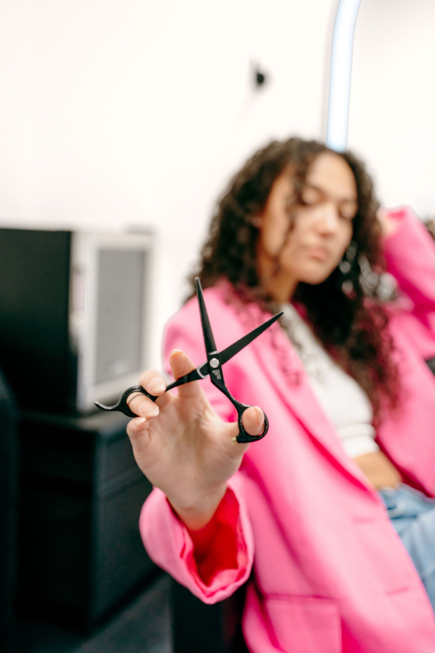 Person in pink blazer holding scissors while cutting in a professional setting.