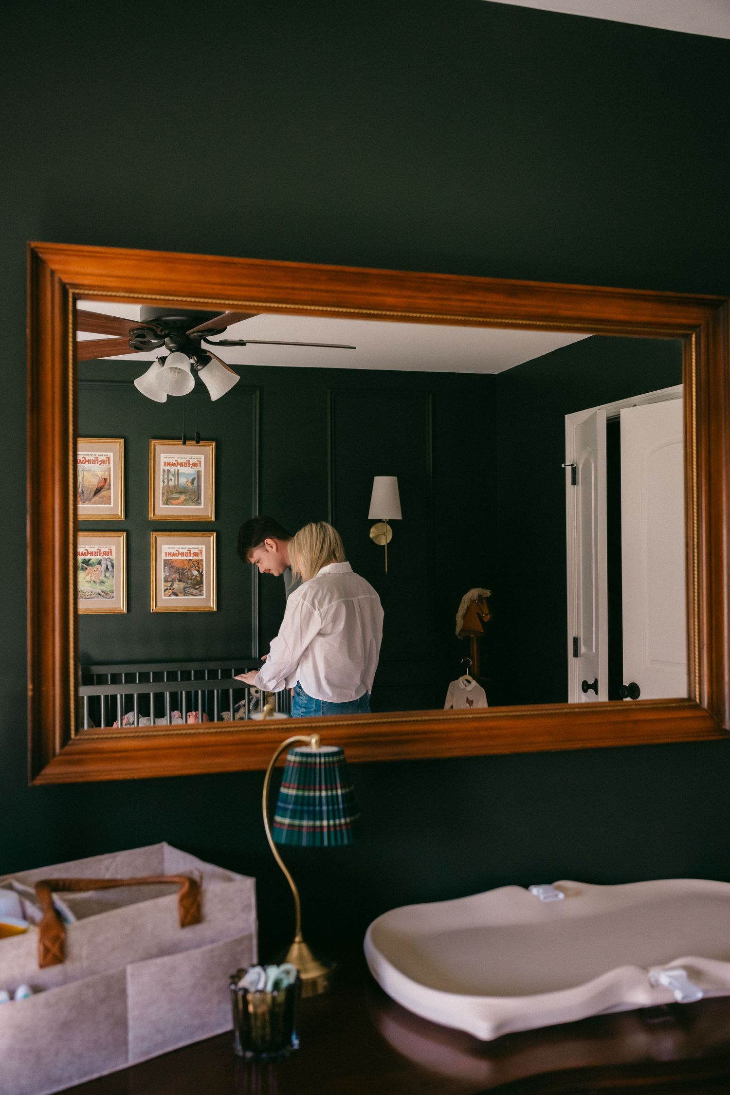 Interior shots of a nursery with dark green walls and wooden accents.