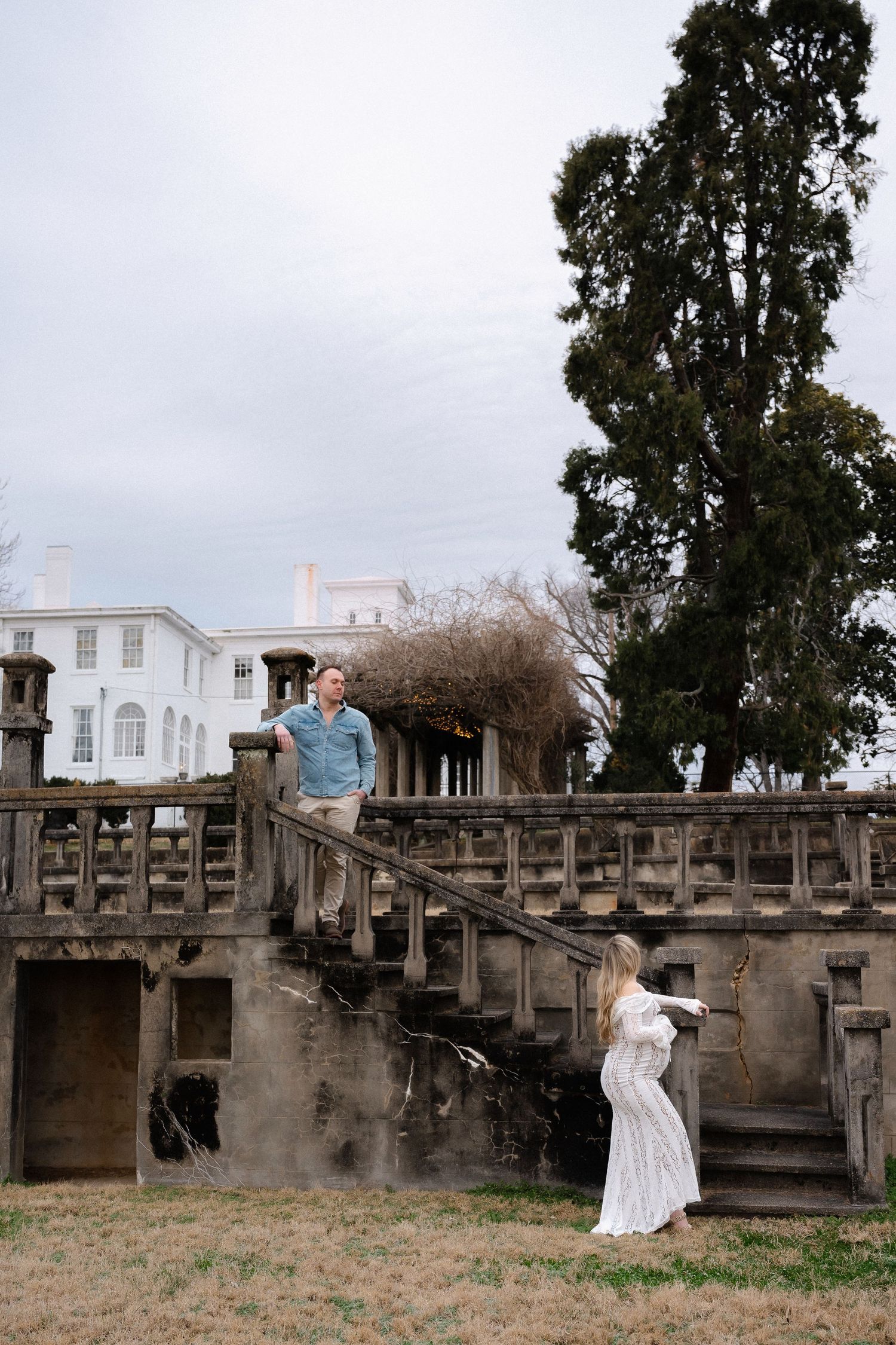 Couple takes romantic photos on historic stone staircase surrounded by trees.