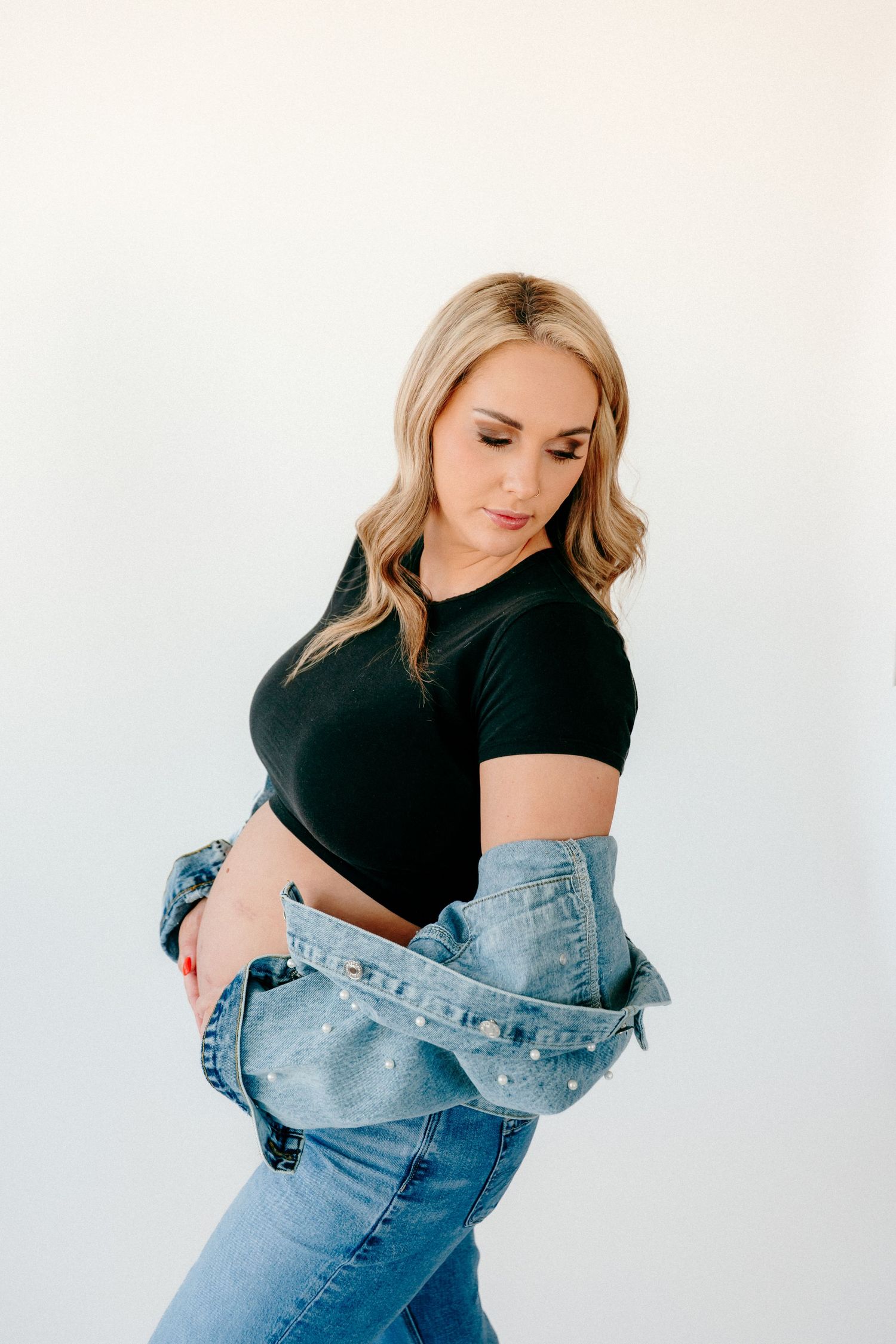 Maternity photography sequence showing a woman in casual wear against a white backdrop.
