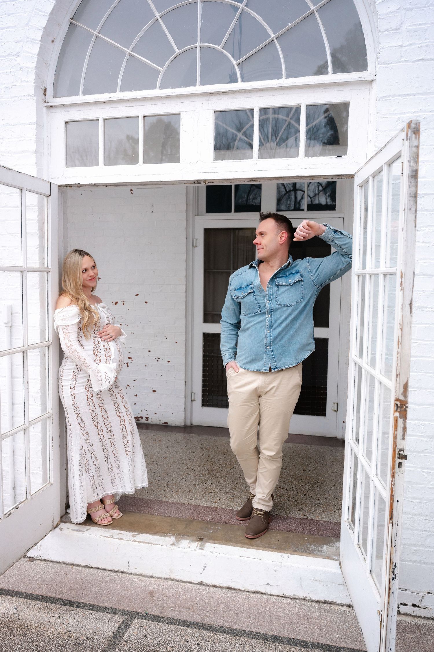 Couple dances playfully in front of white-painted doorway with glass panels.