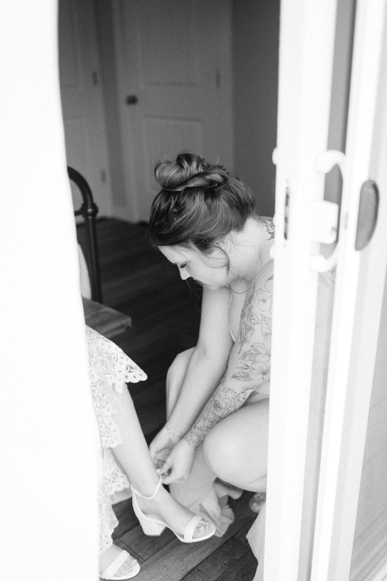 A person putting on white shoes while sitting in a bright room.