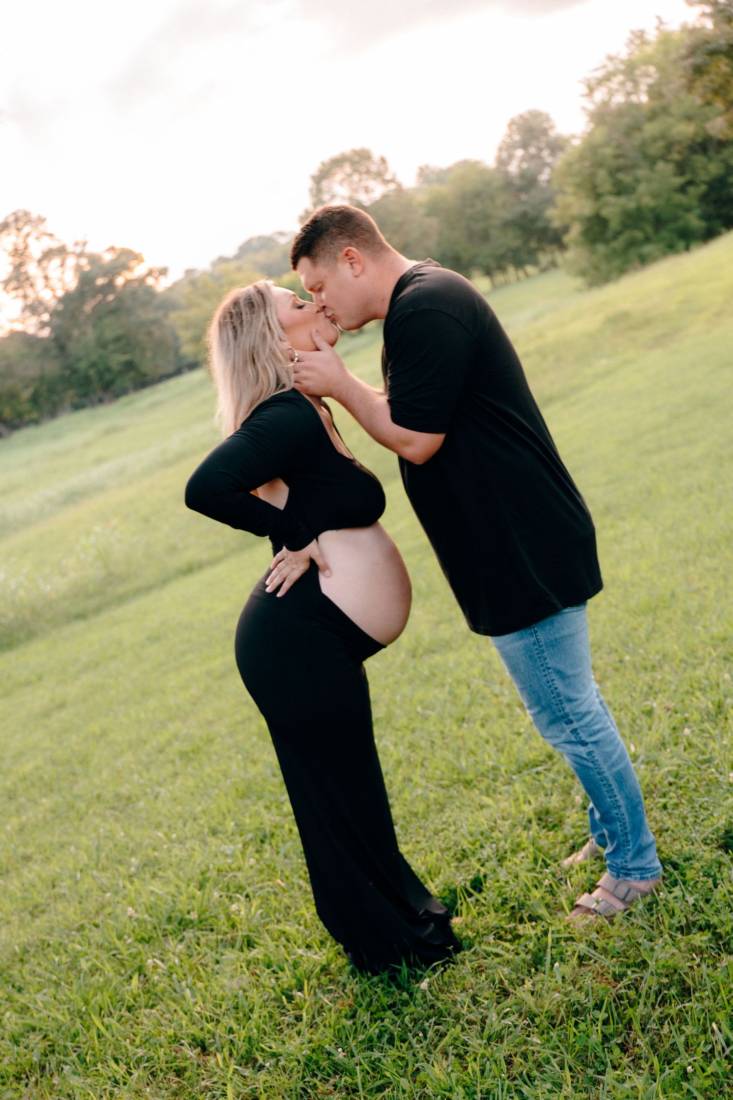 Intimate maternity couple photos in grassy field at sunset.