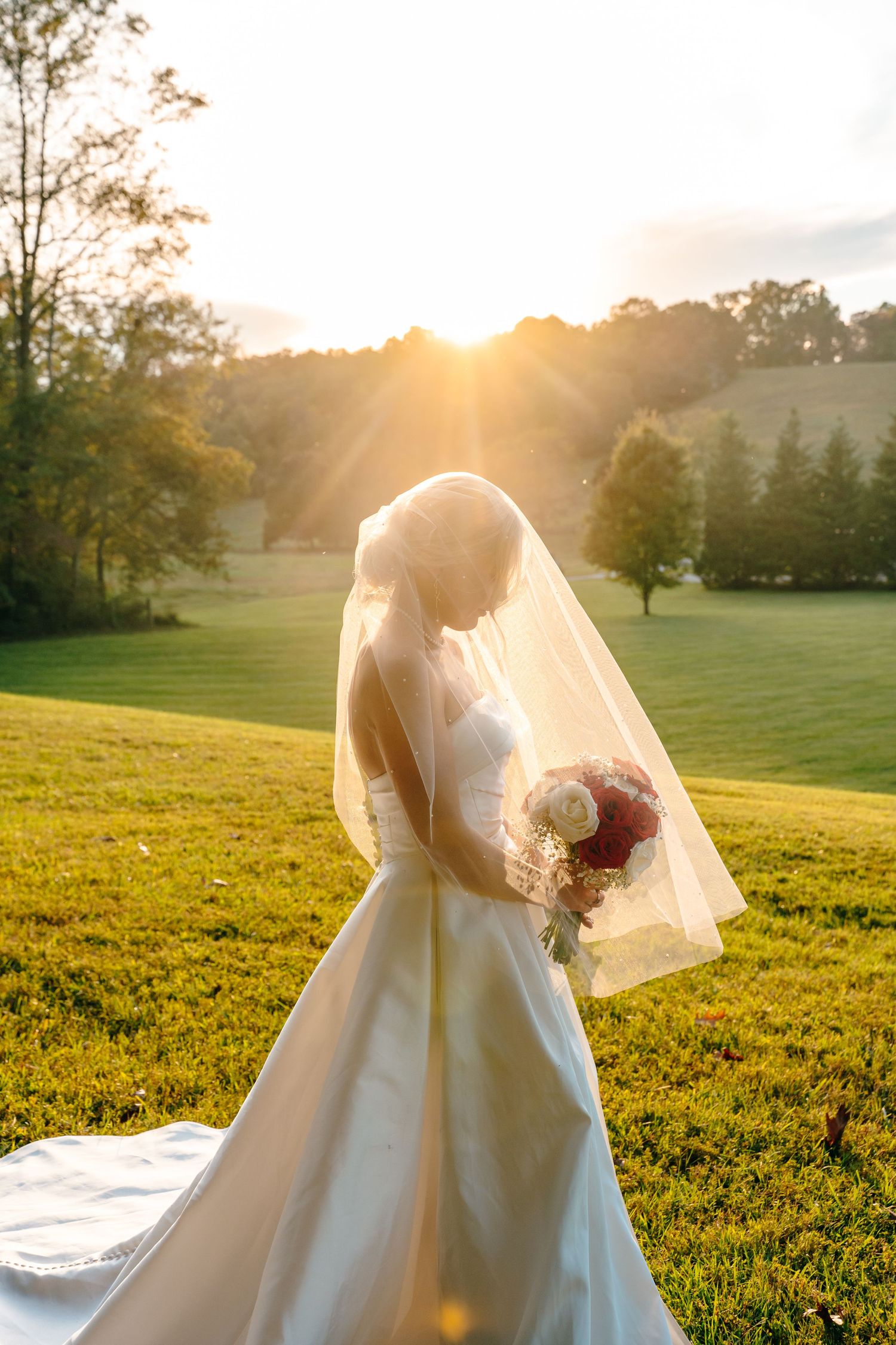 Sunset bridal portraits featuring an elegant white ballgown in a golden meadow.