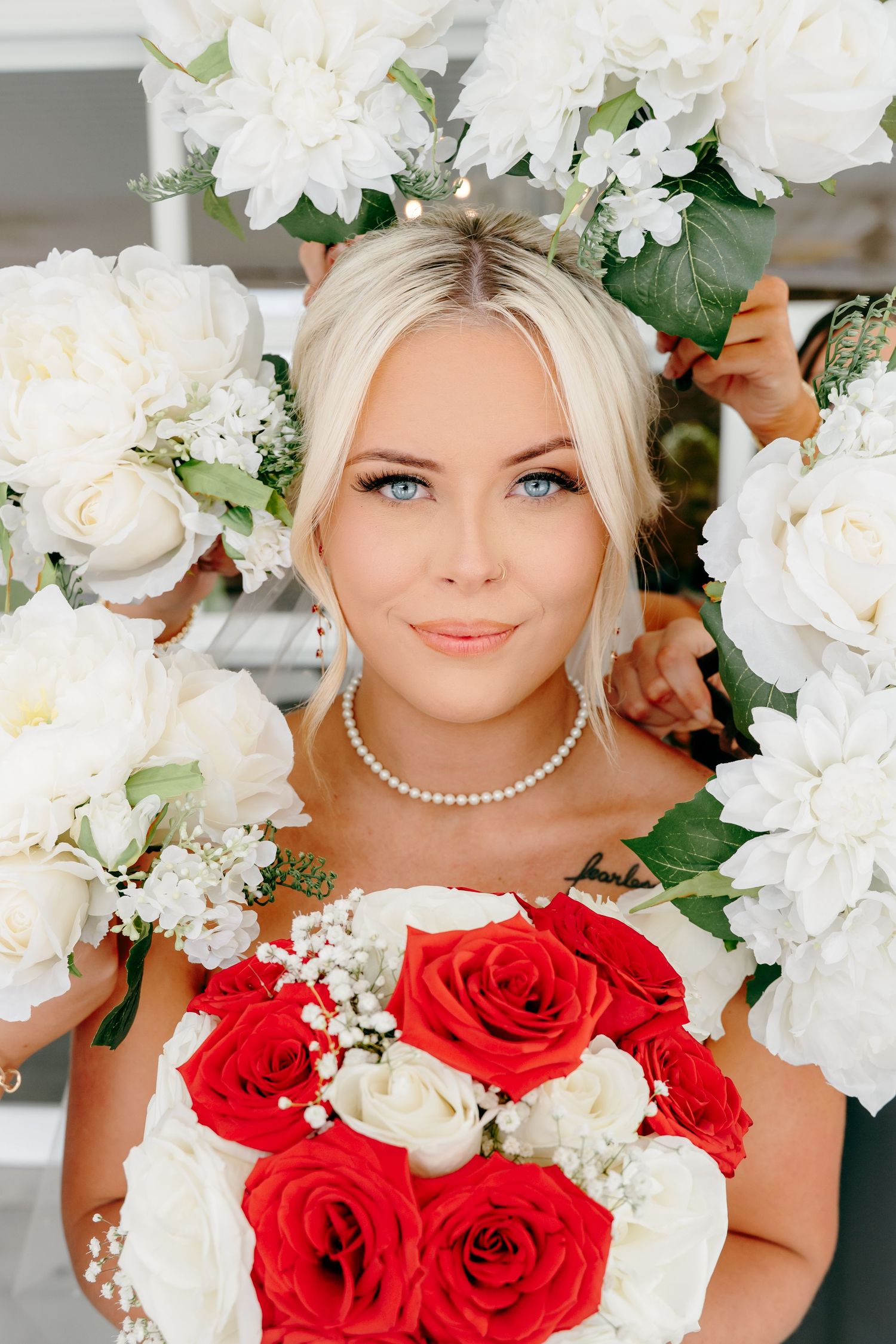 Wedding bouquet features stunning red roses and white flowers with pearl accents.