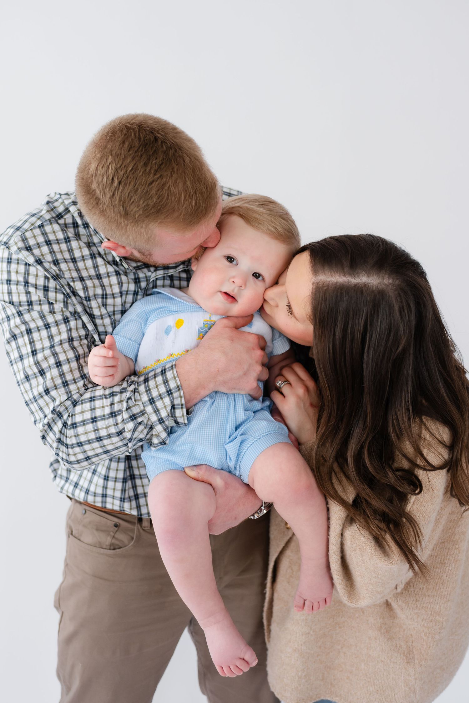 Sweet family moment captured in a series of tender kisses and embraces against white background.