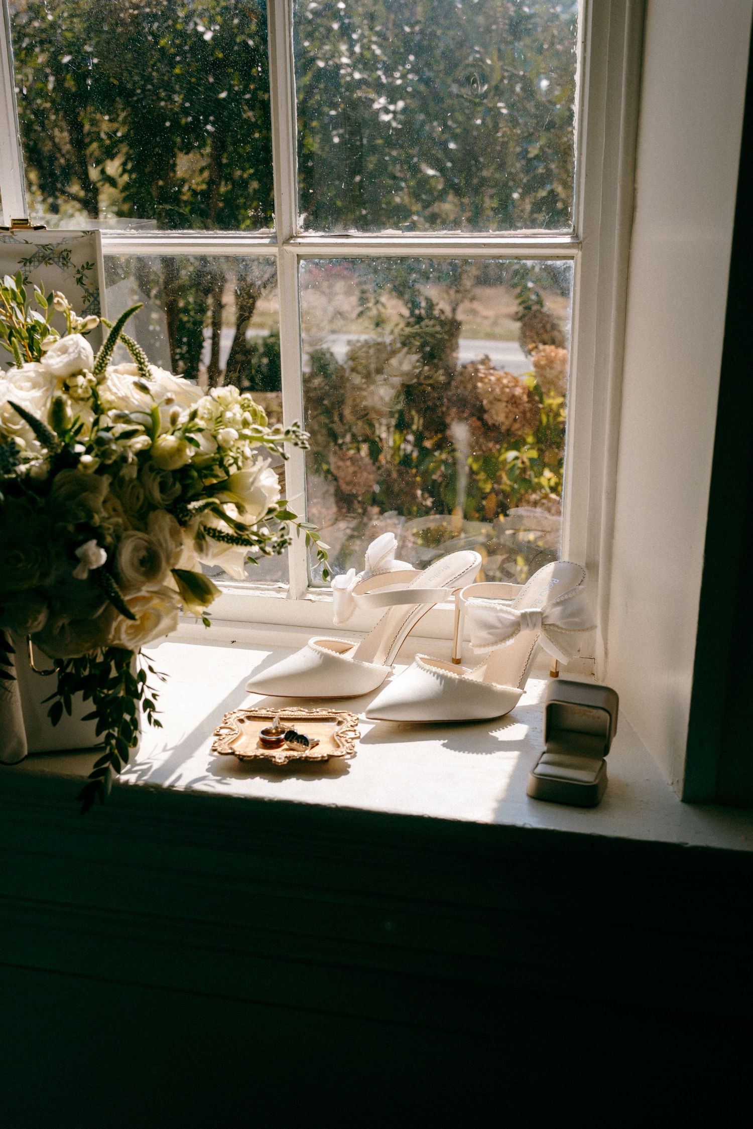 Elegant white floral arrangements and decor displayed along sunny windowsill.