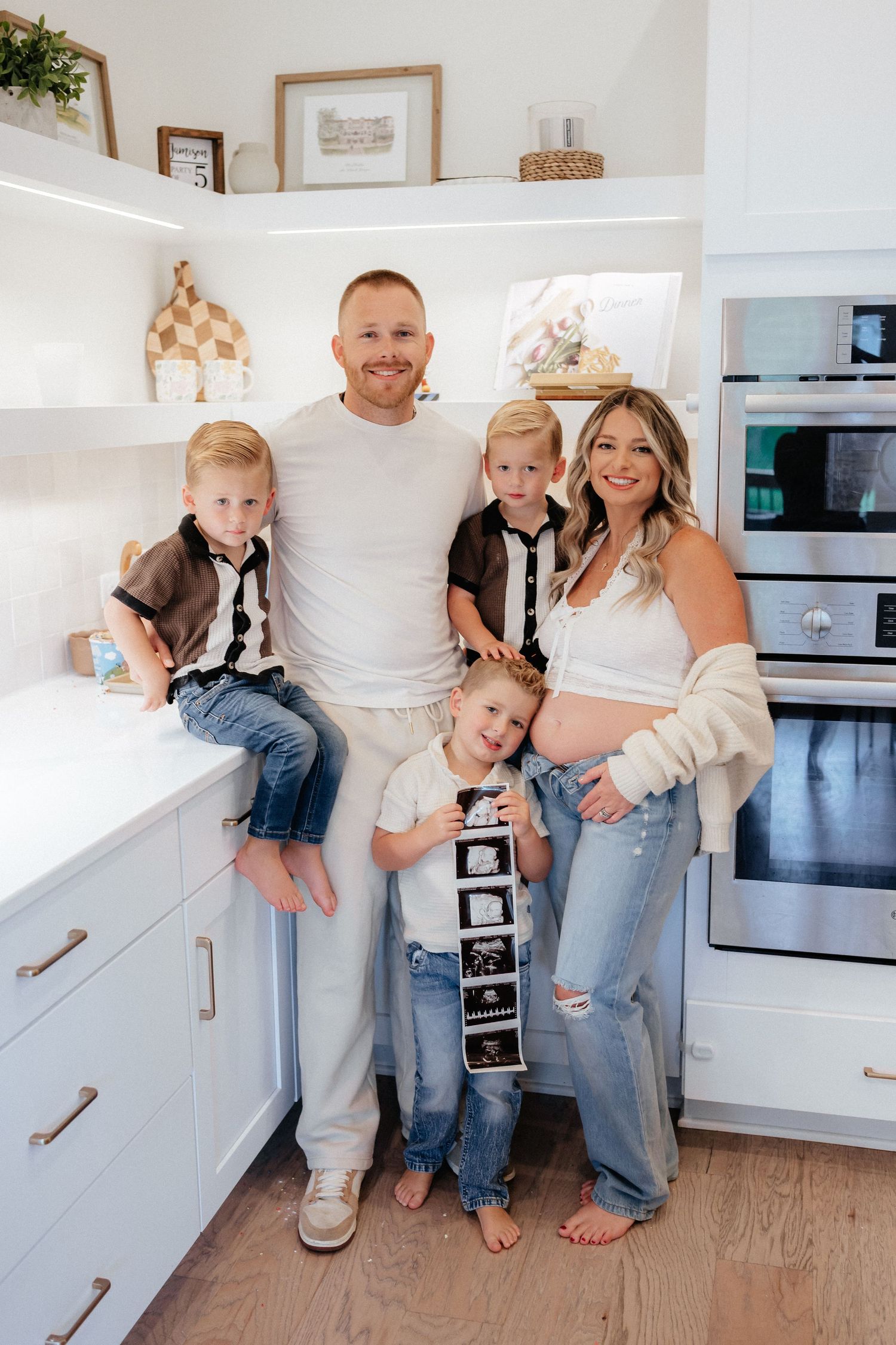 A family shares a joyful moment together in their modern white kitchen.
