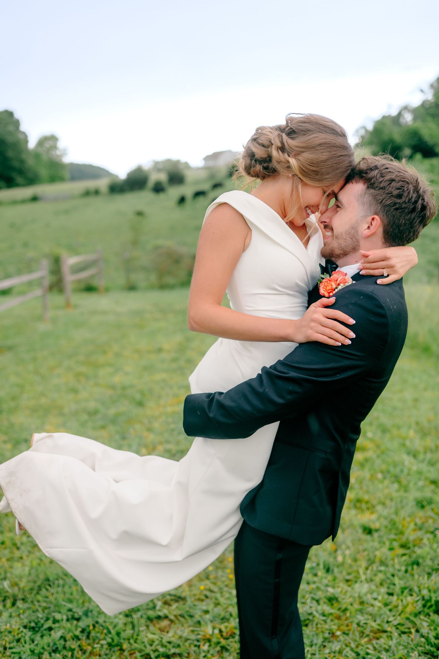 Romantic moment between newlyweds in green field with rolling hills.