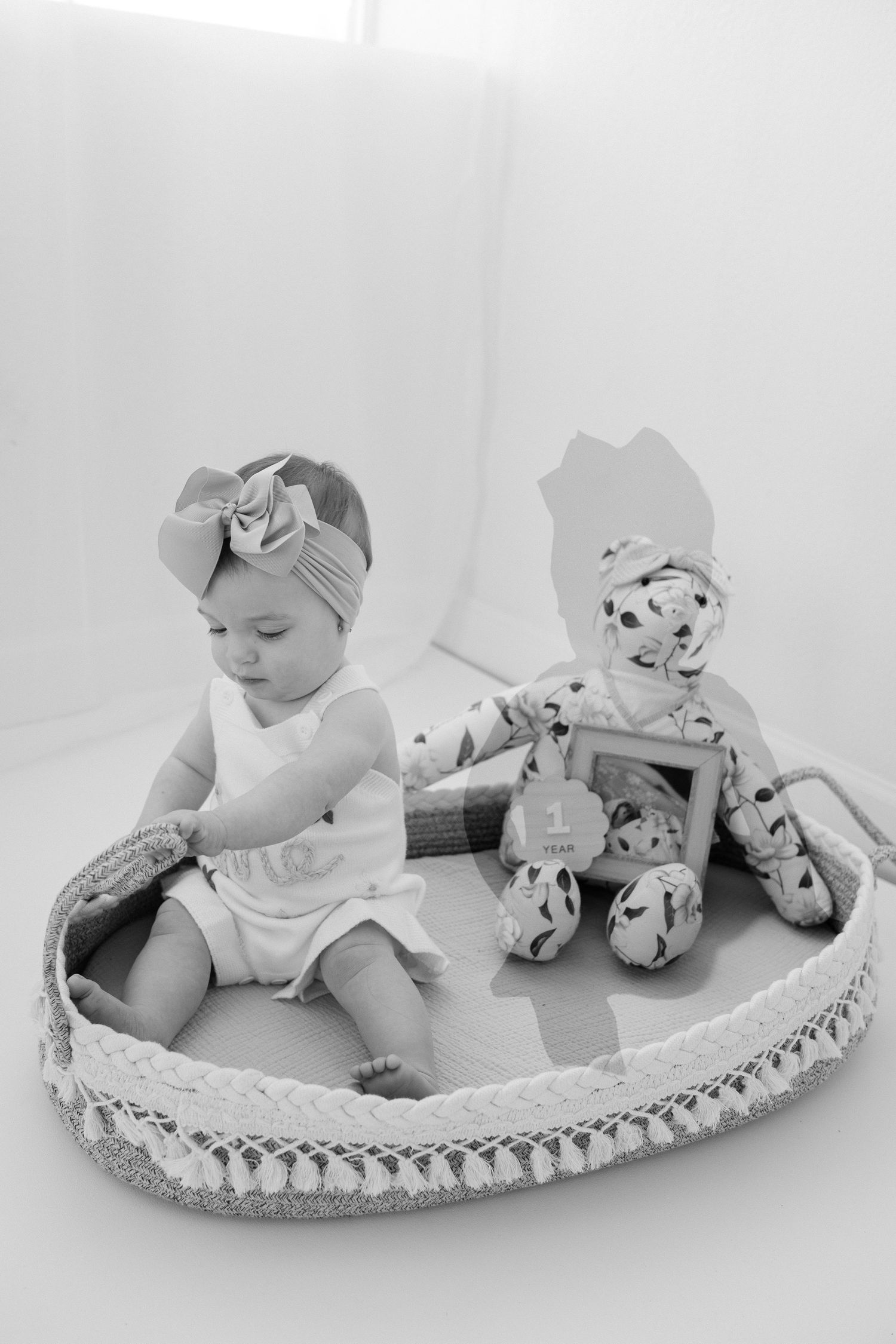 Black and white photo series showing a baby with stuffed dalmatian toys on a curved crescent-shaped cushion.
