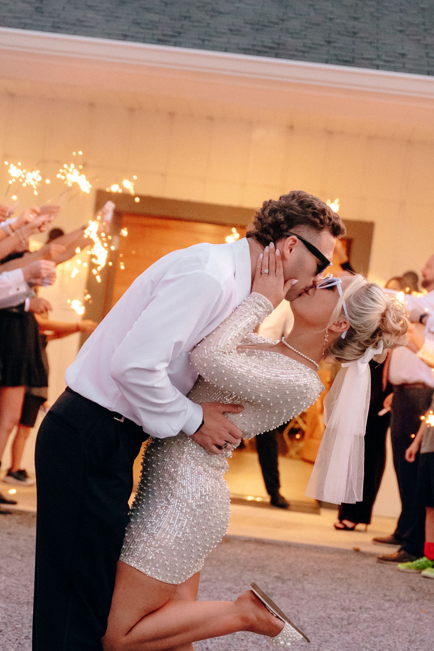 Romantic wedding dance dip with couple embracing on outdoor patio during evening reception.