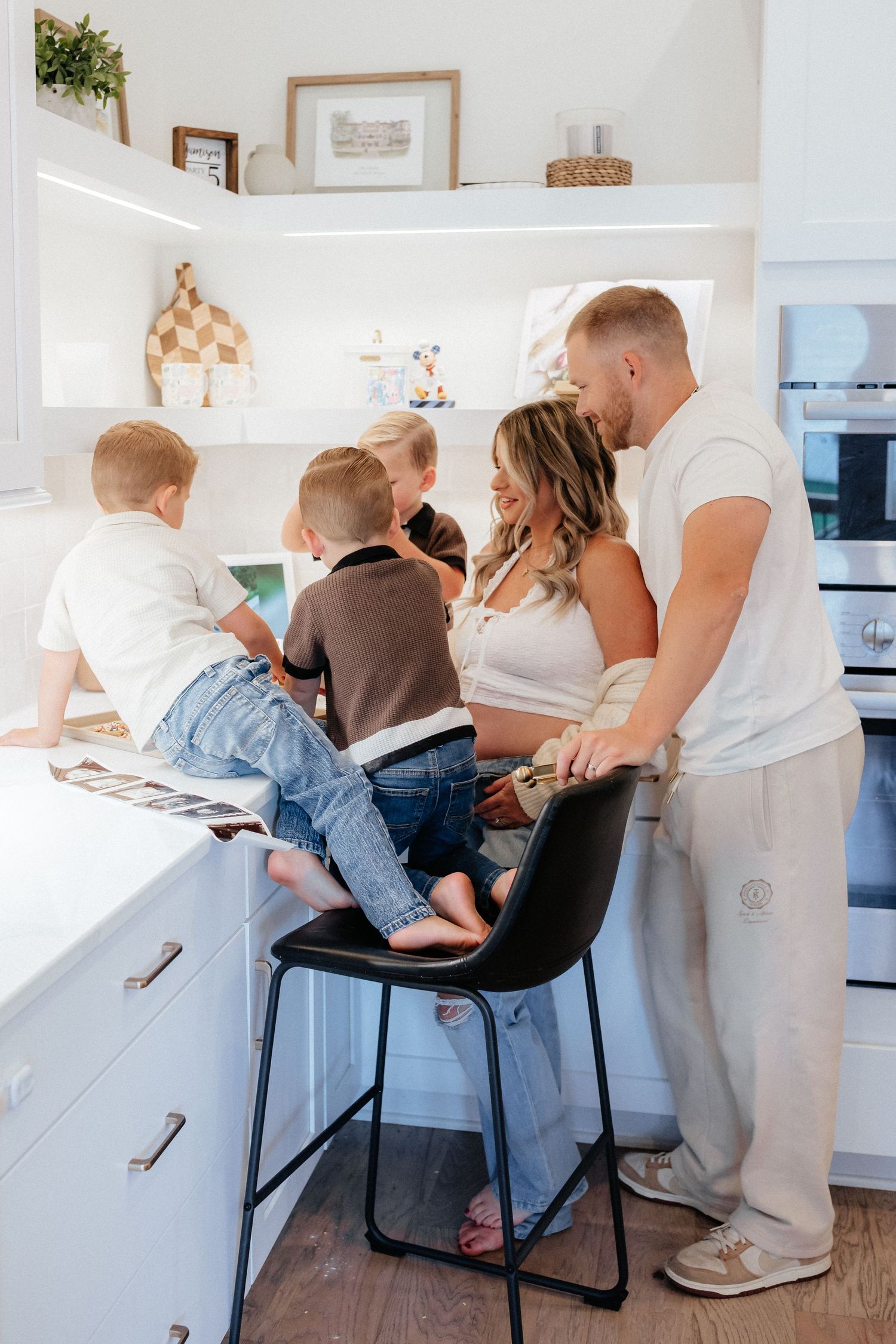 A family gathers around a kitchen counter looking at something together.