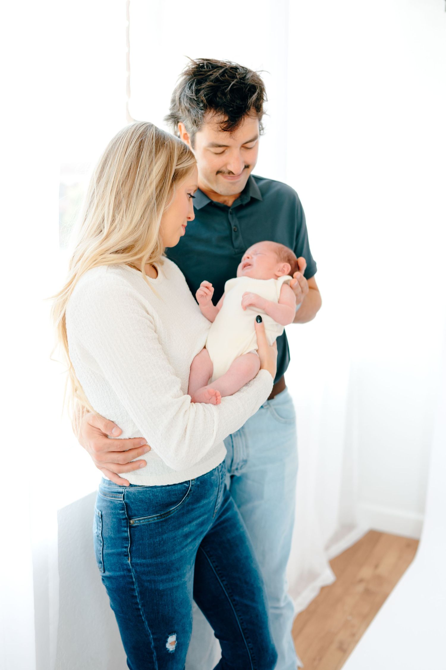 A series of candid family moments captured in a bright white studio setting.