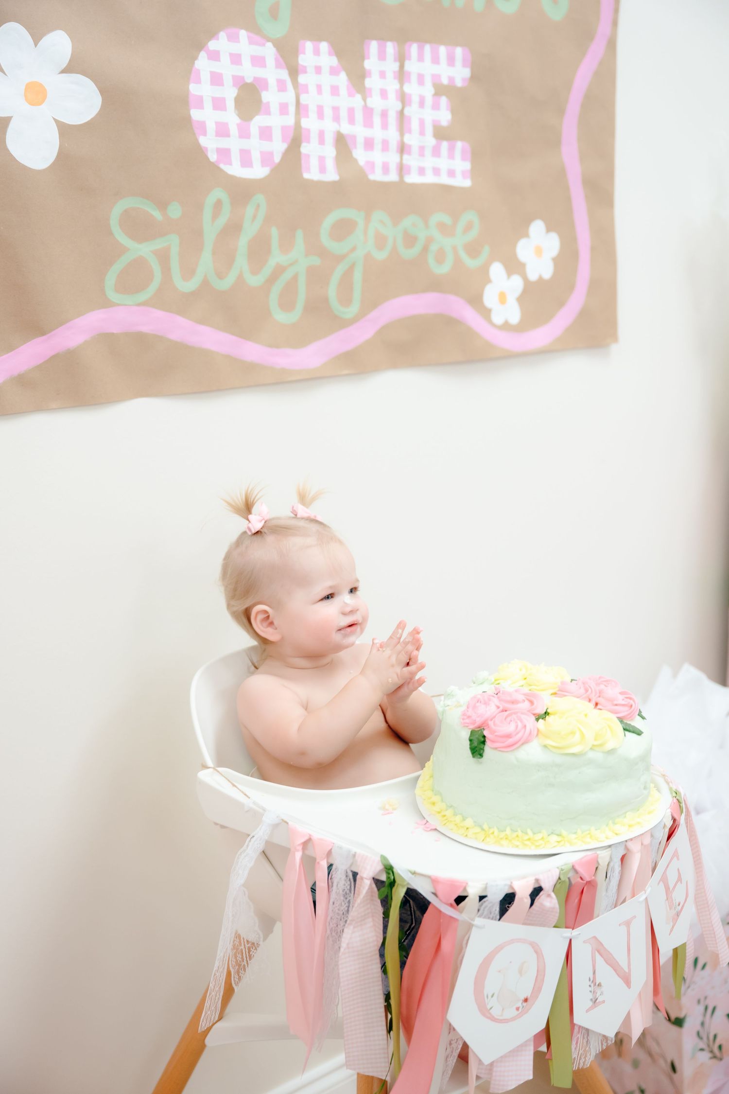 First birthday party setup with pastel decorations and high chair for cake smash celebration.