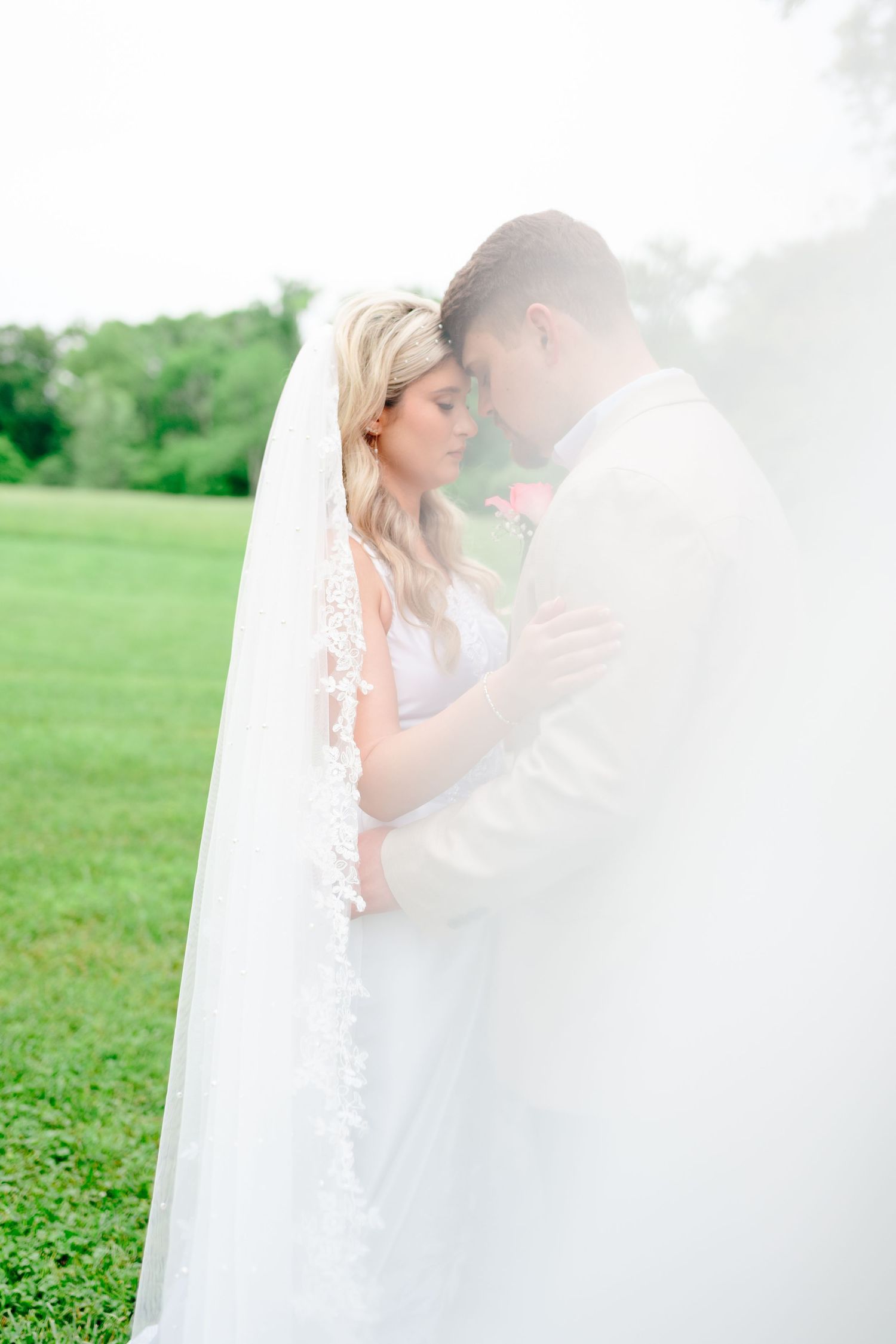 Dreamy wedding photos through sheer white veil in outdoor garden setting.