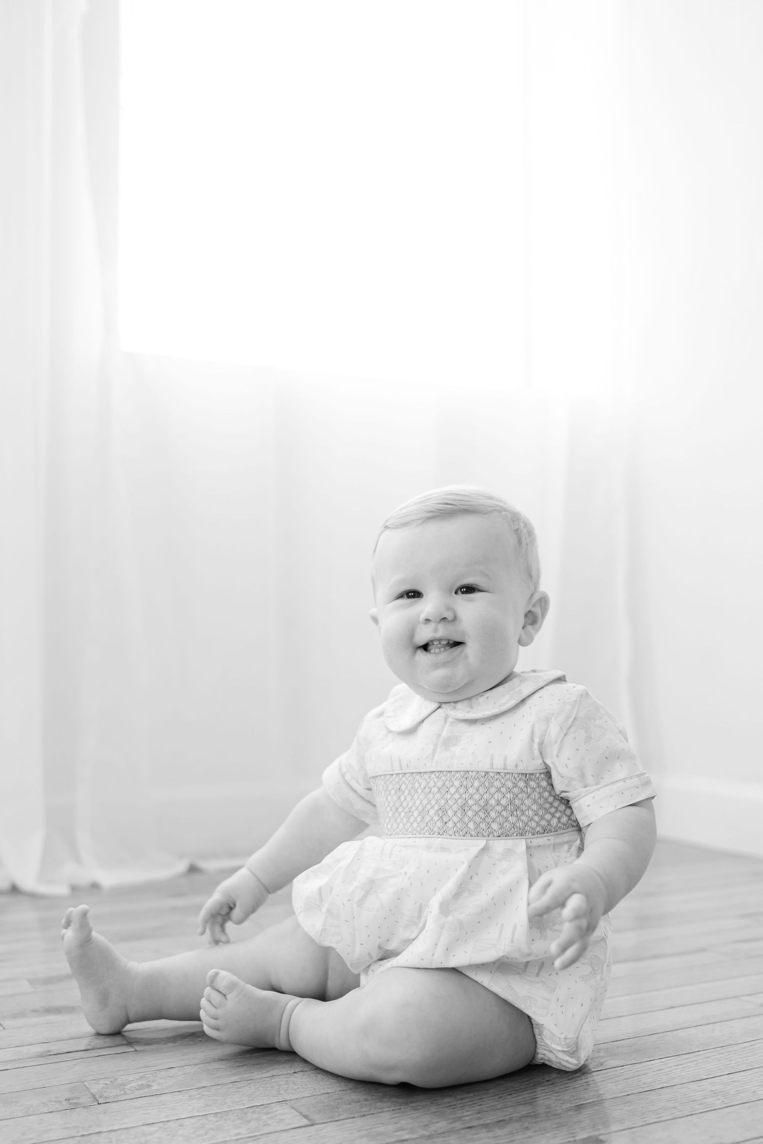 A series of black and white photos showing a baby in white clothing sitting on a wooden floor.