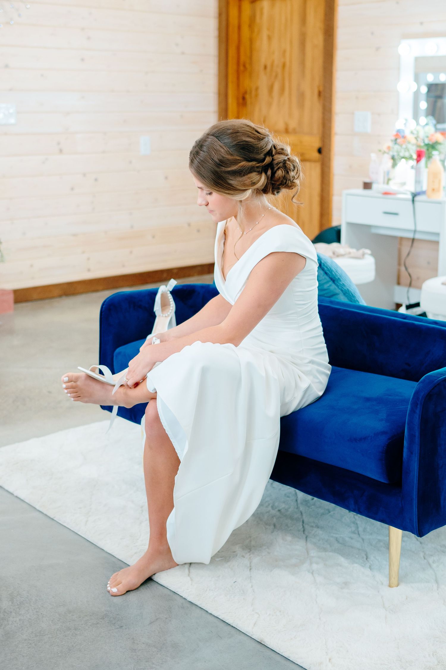 Wedding preparation scene with white dress on blue velvet couch.