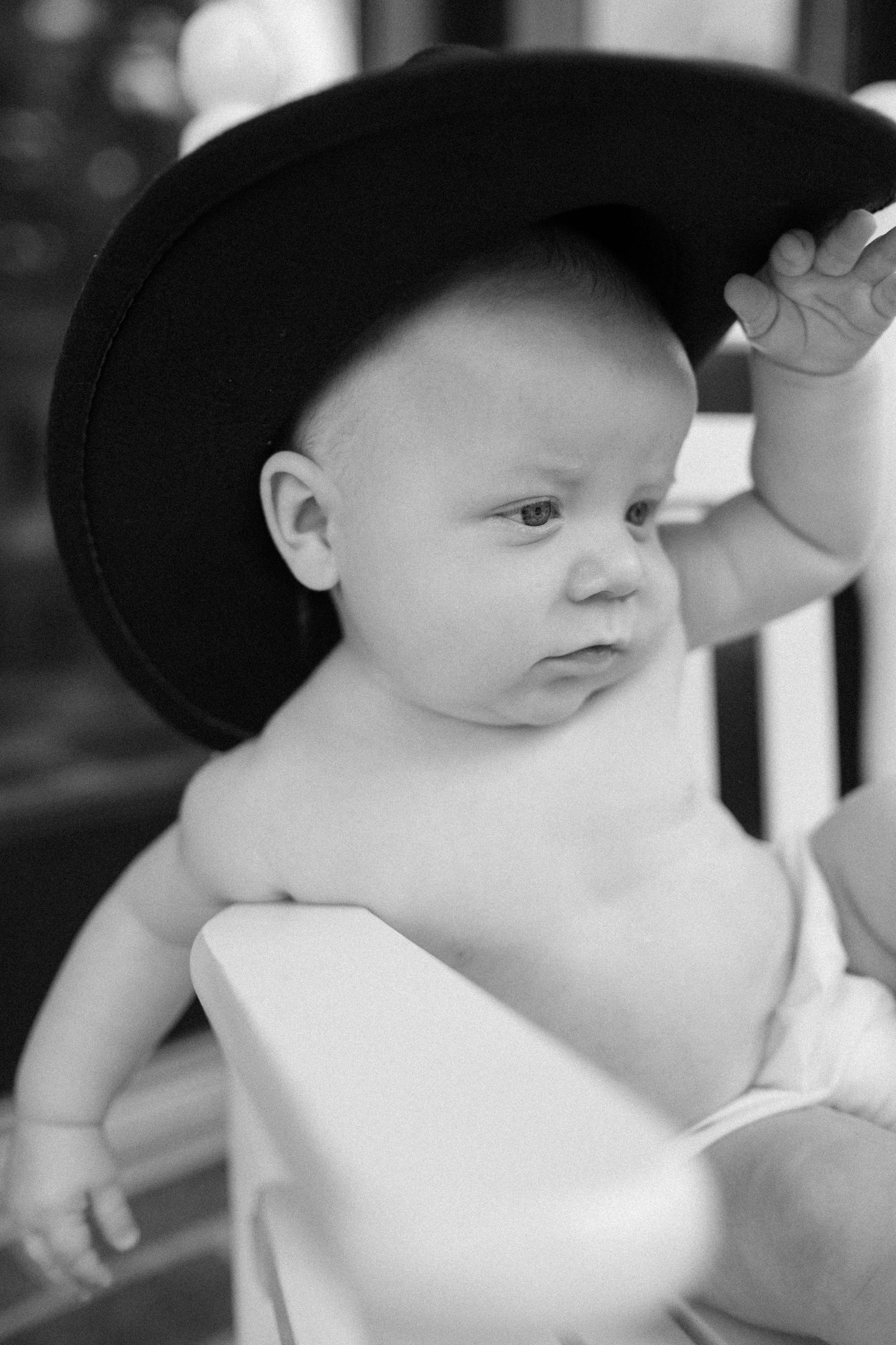A series of black and white close-up photos showing a baby wearing a dark hat looking in different directions.