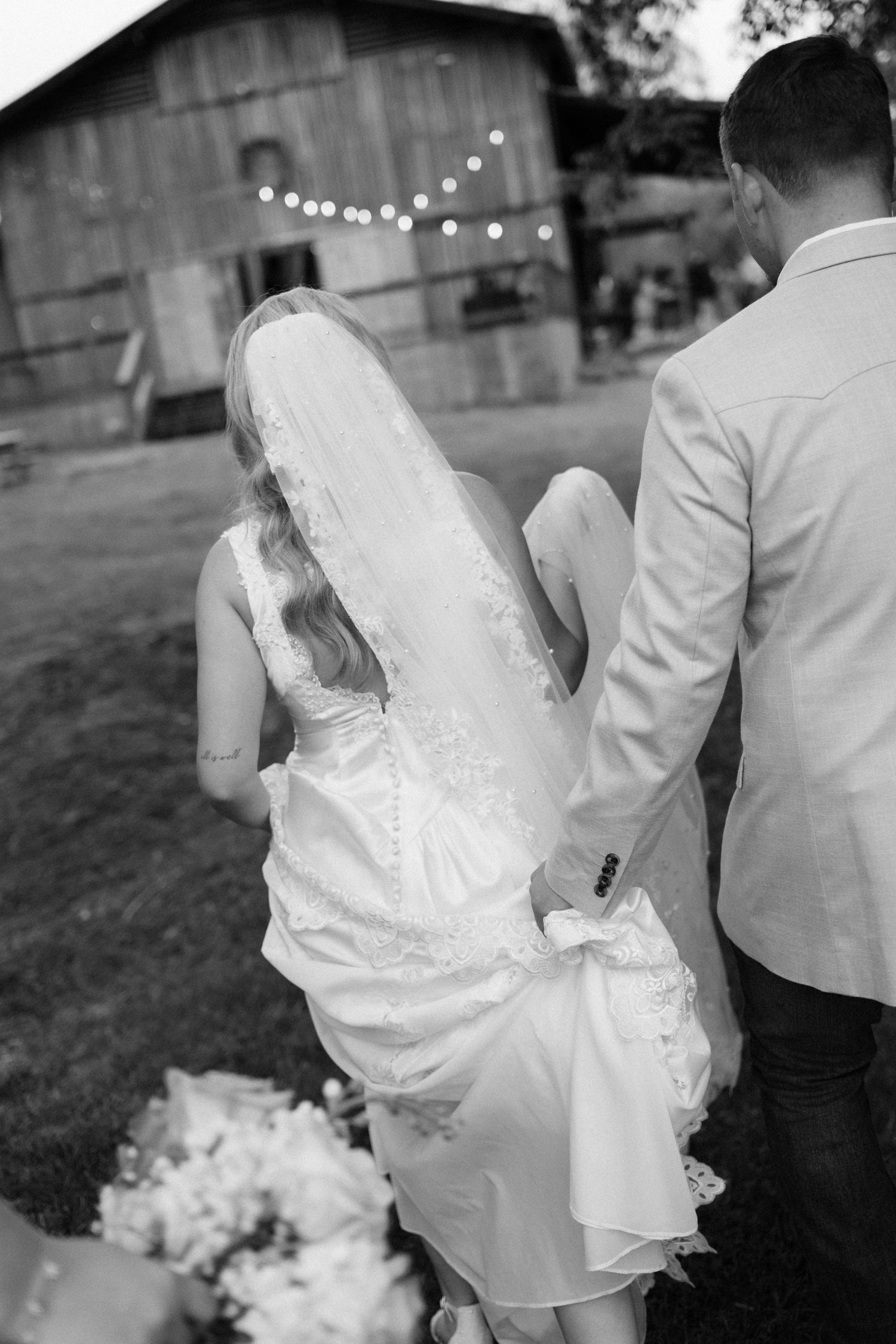 Black and white wedding photo showing couple walking together outdoors.
