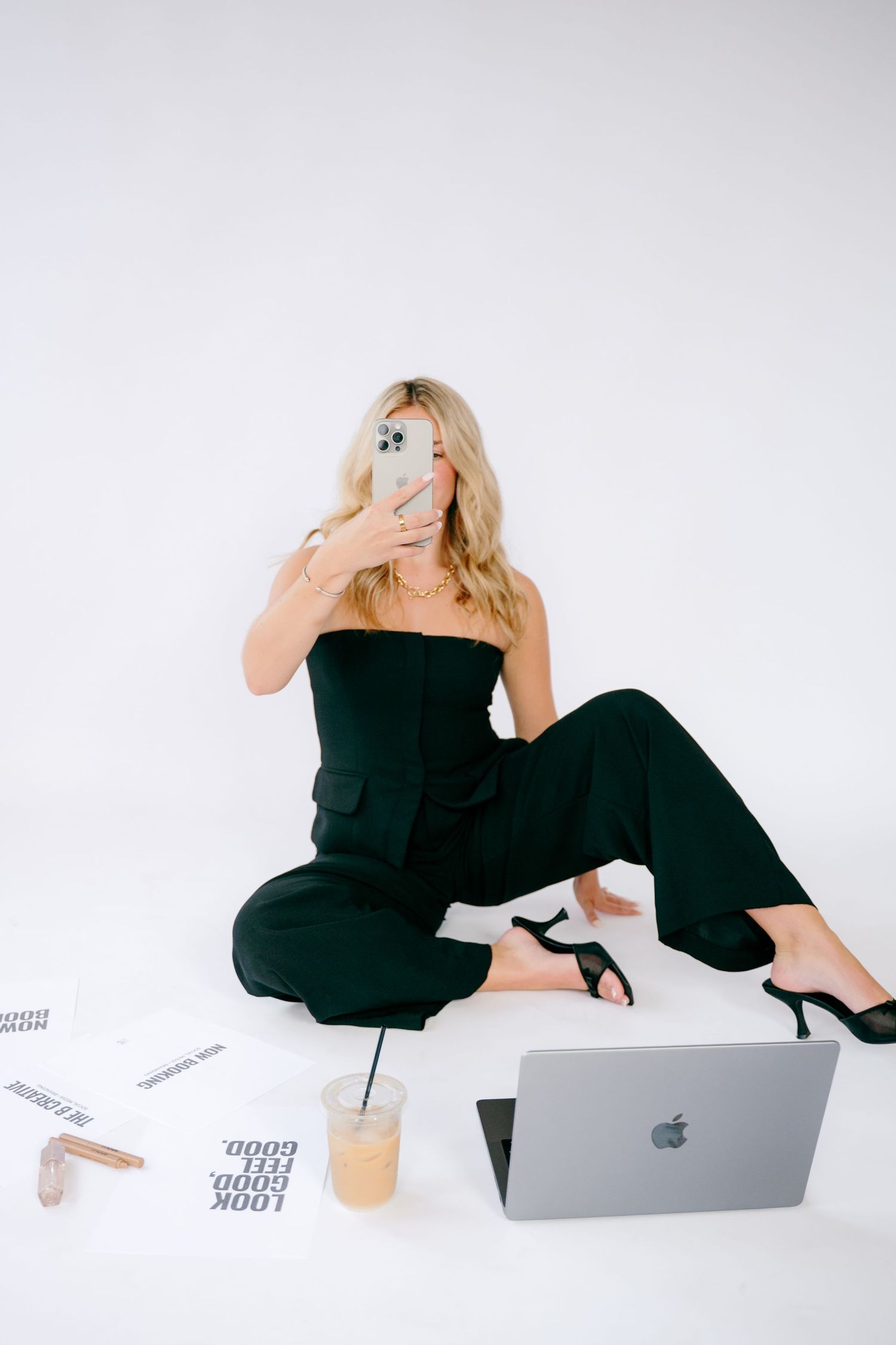 Modern workspace setup with laptop and papers featuring a black jumpsuit outfit.