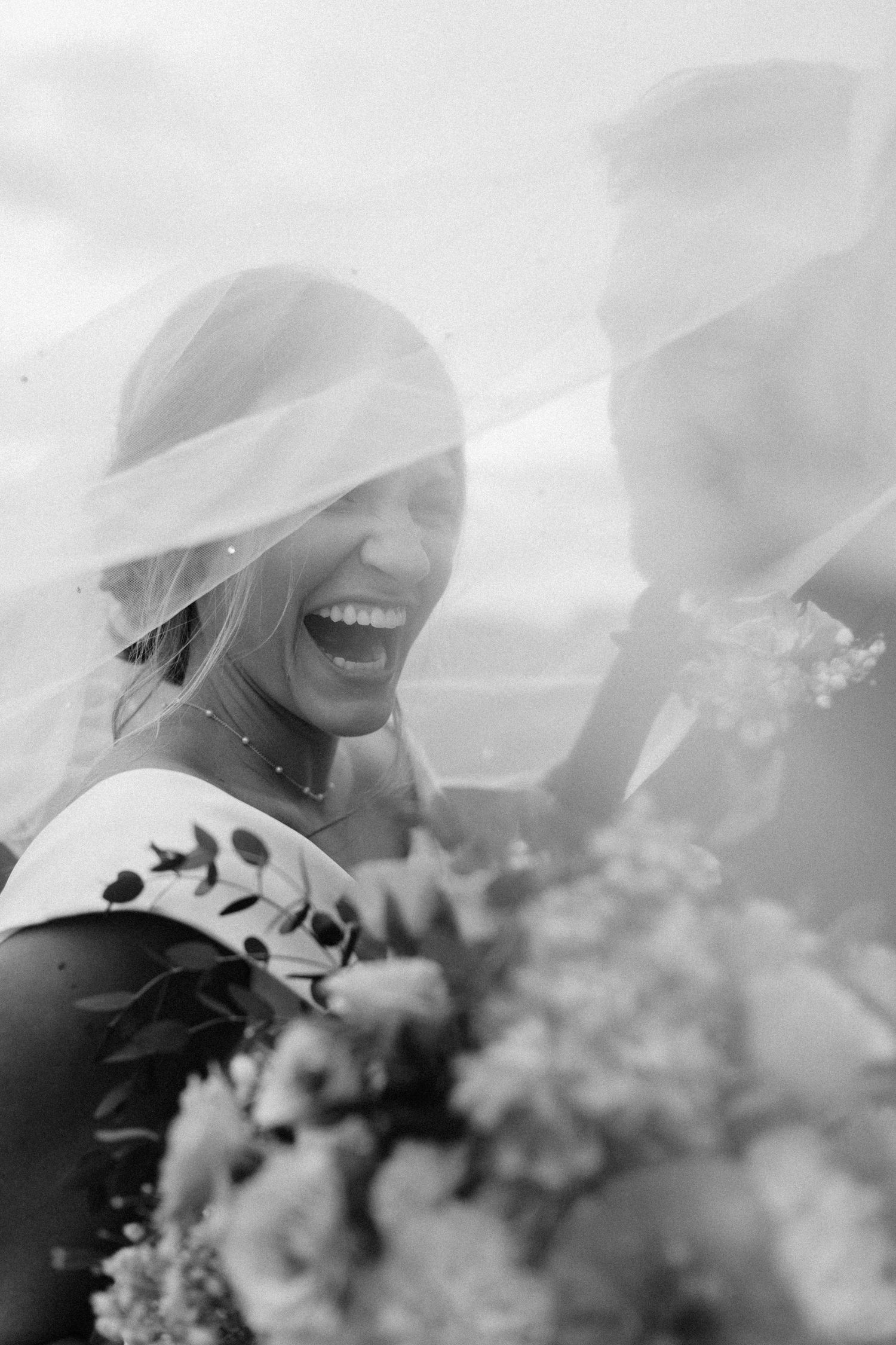 Artistic black and white bridal portrait through delicate veil.