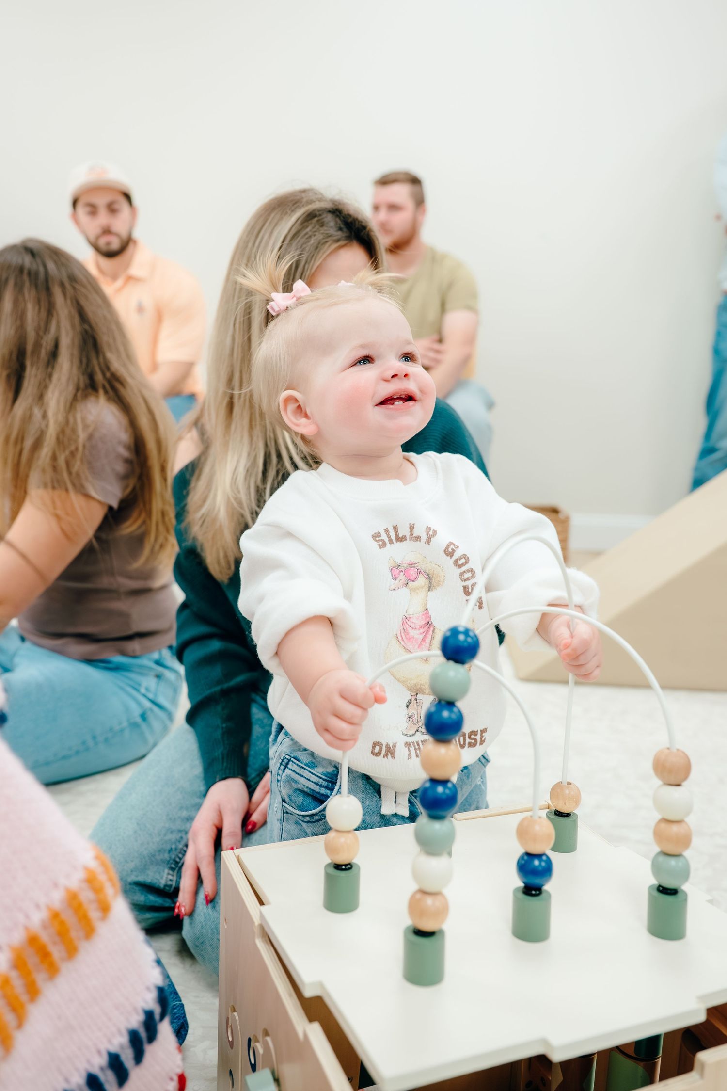 A child plays with colorful wooden peg toys on a white table during an activity session.