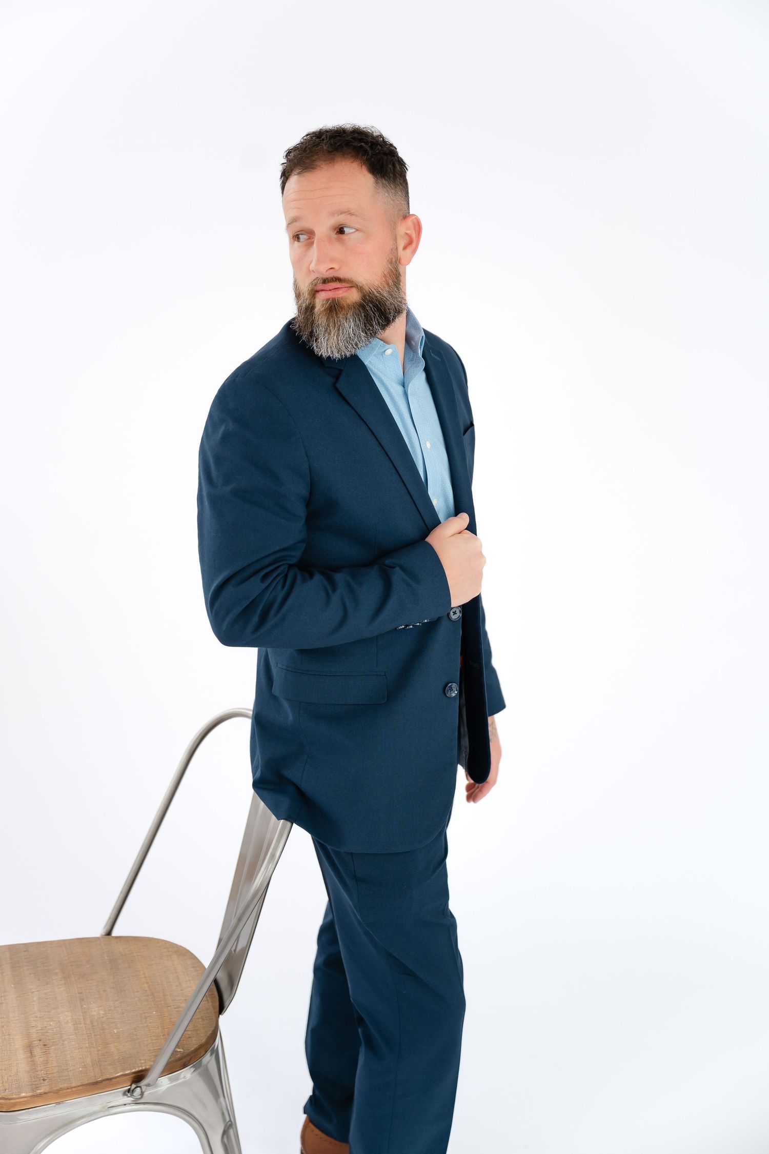 A person in a navy suit poses with a chair against a white background in four different positions.