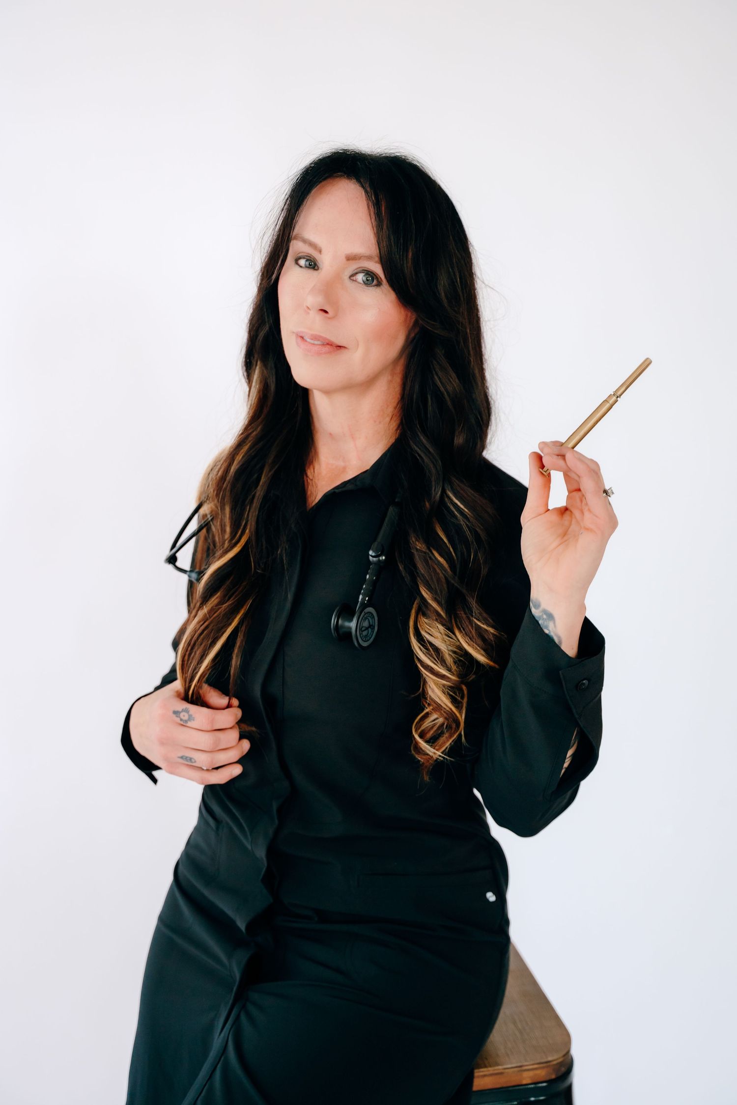 Fashion model in black hoodie poses against white background in four different poses with hair styling tools.