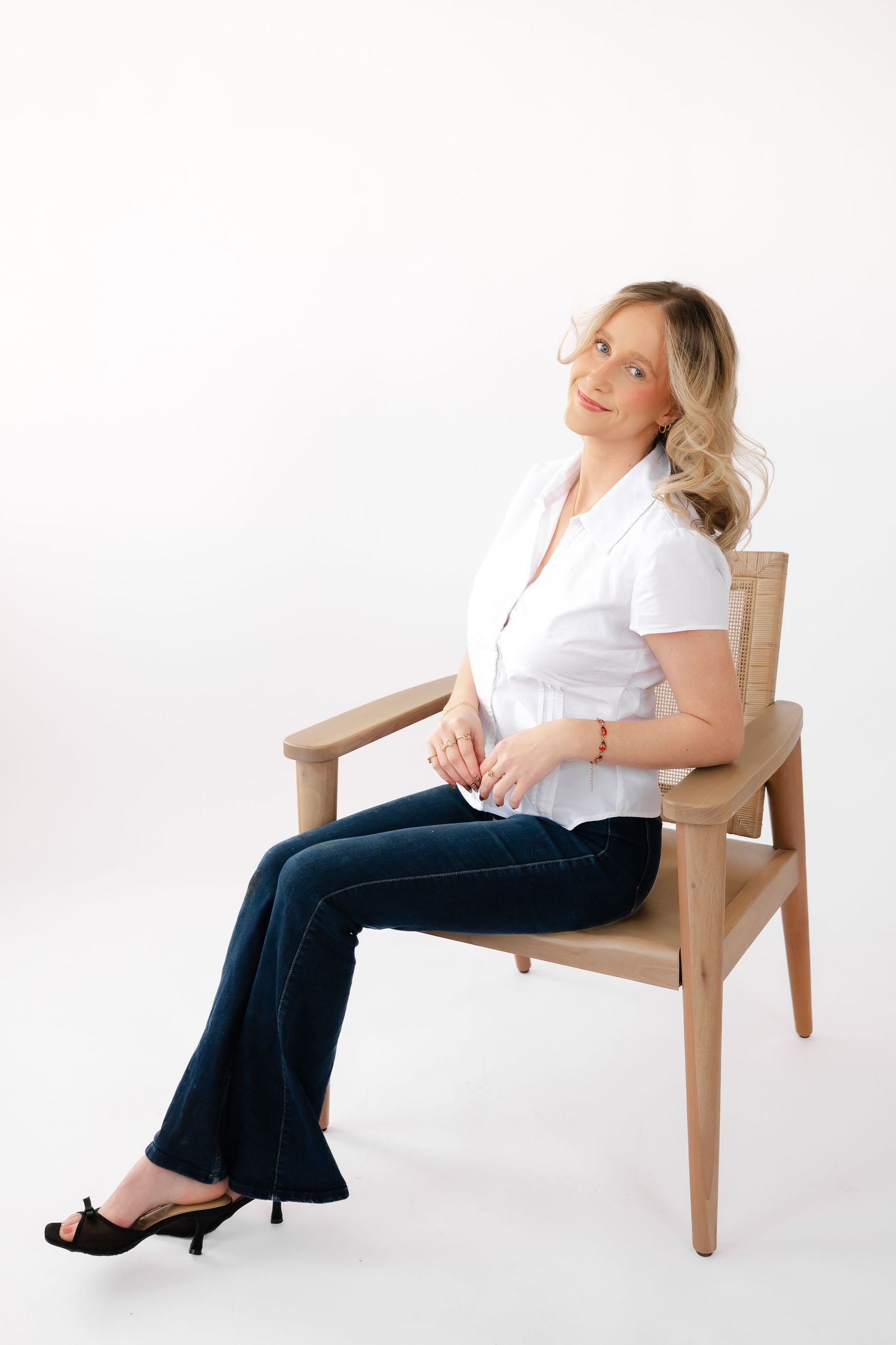 Person in white shirt and dark pants lounges in wooden chair against white background in multiple poses.