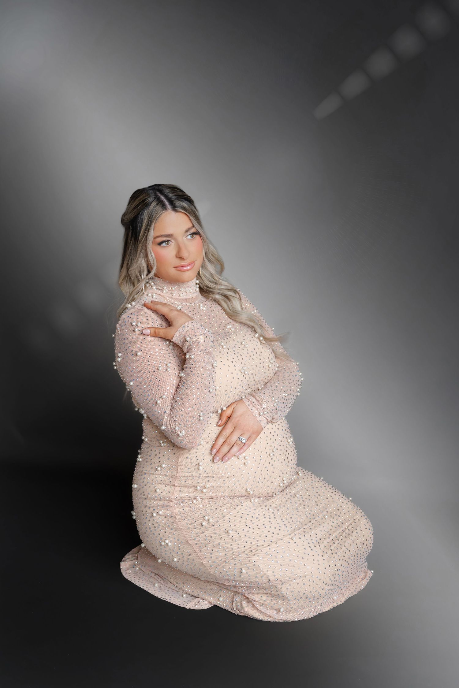 Maternity portrait featuring woman in sparkly cream-colored gown.