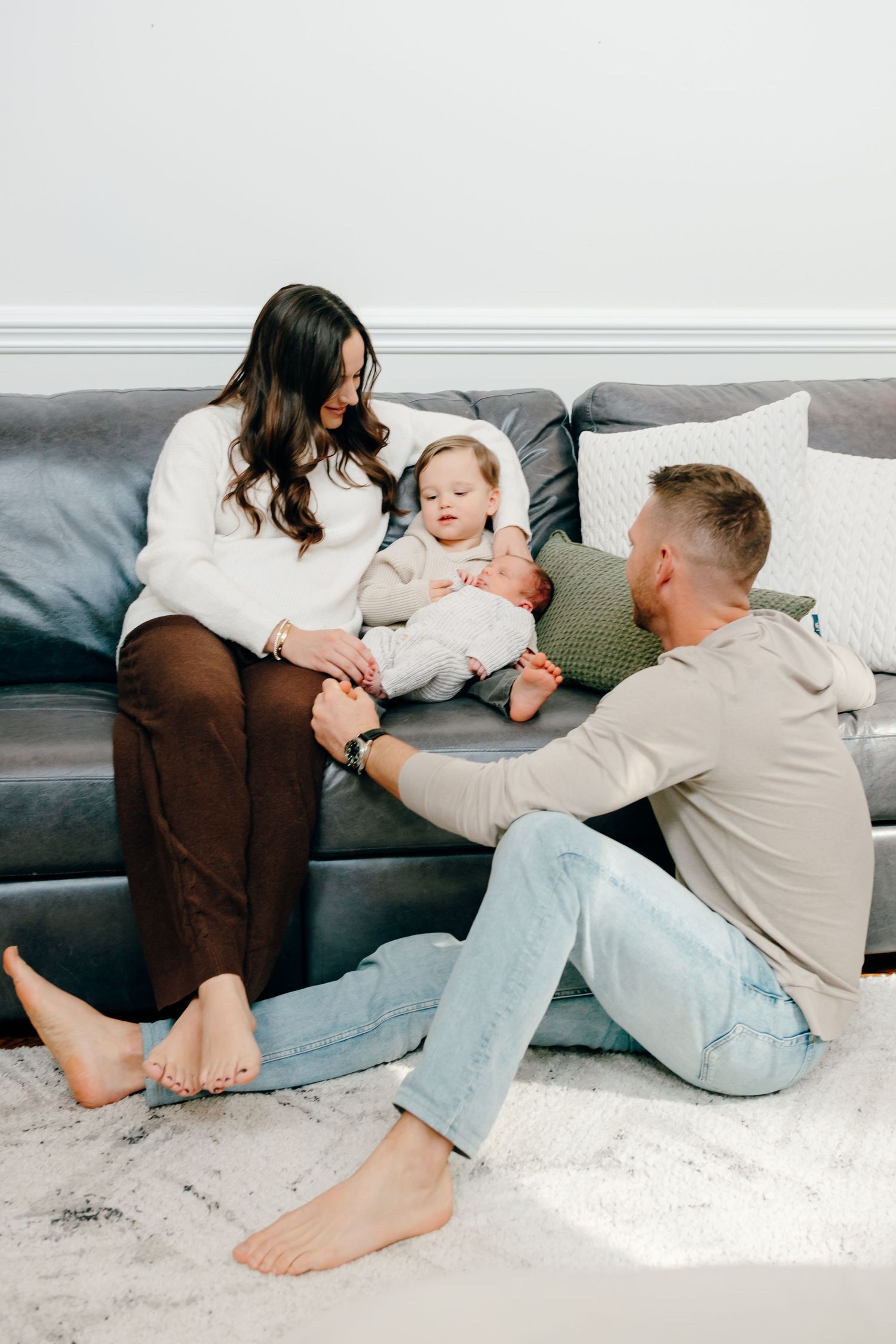 Family relaxing together on grey couch sharing playful moments.
