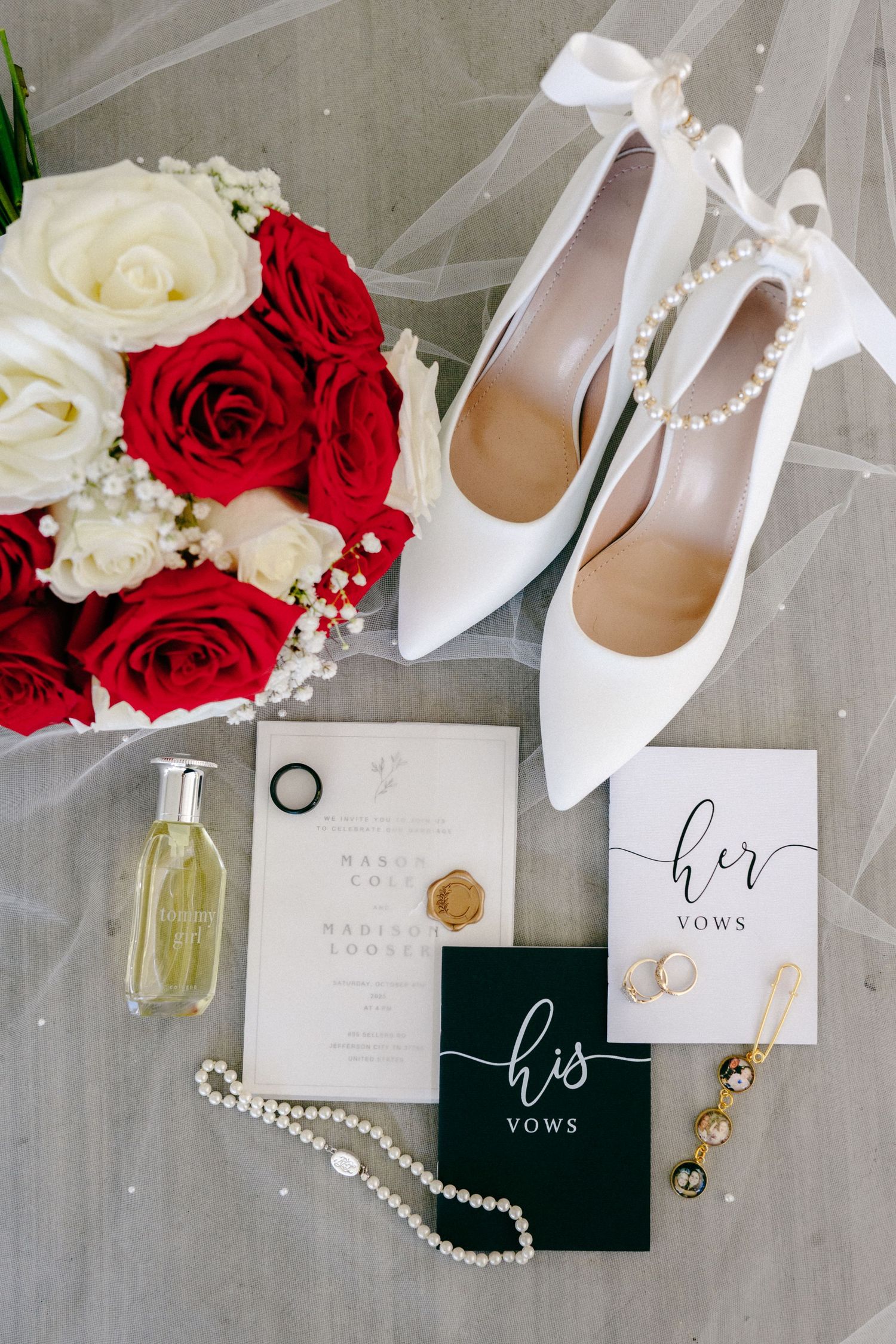 Wedding details flatlay with white shoes, red roses, pearls and invitation cards.